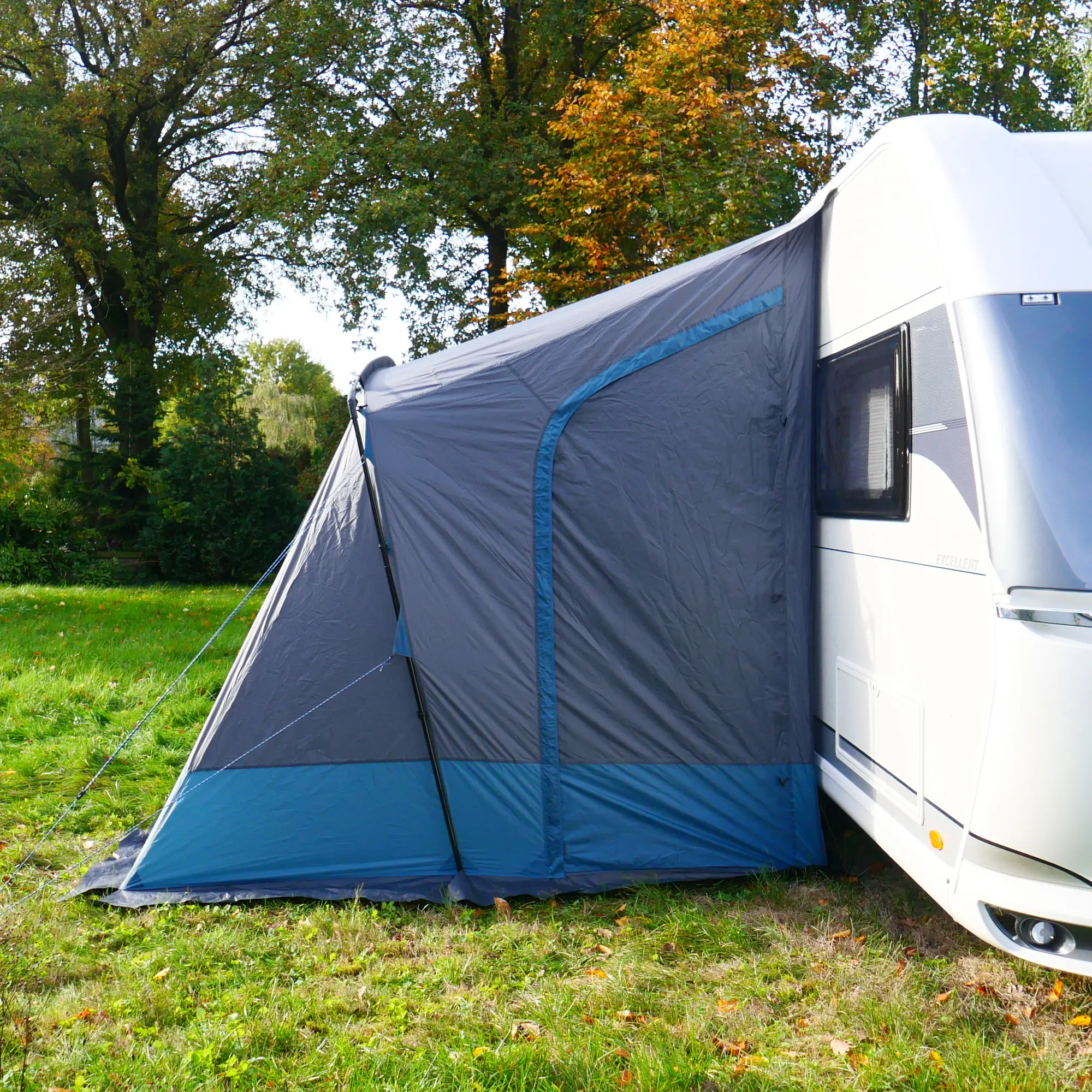 Vorzelt your GEAR Pampero 280 am Wohnwagen, grau-blau, mit großem Fenster und zwei Eingängen, wetterfestes Material, auf einer Wiese aufgebaut, ideal als Teilvorzelt für Caravan-Reisen.