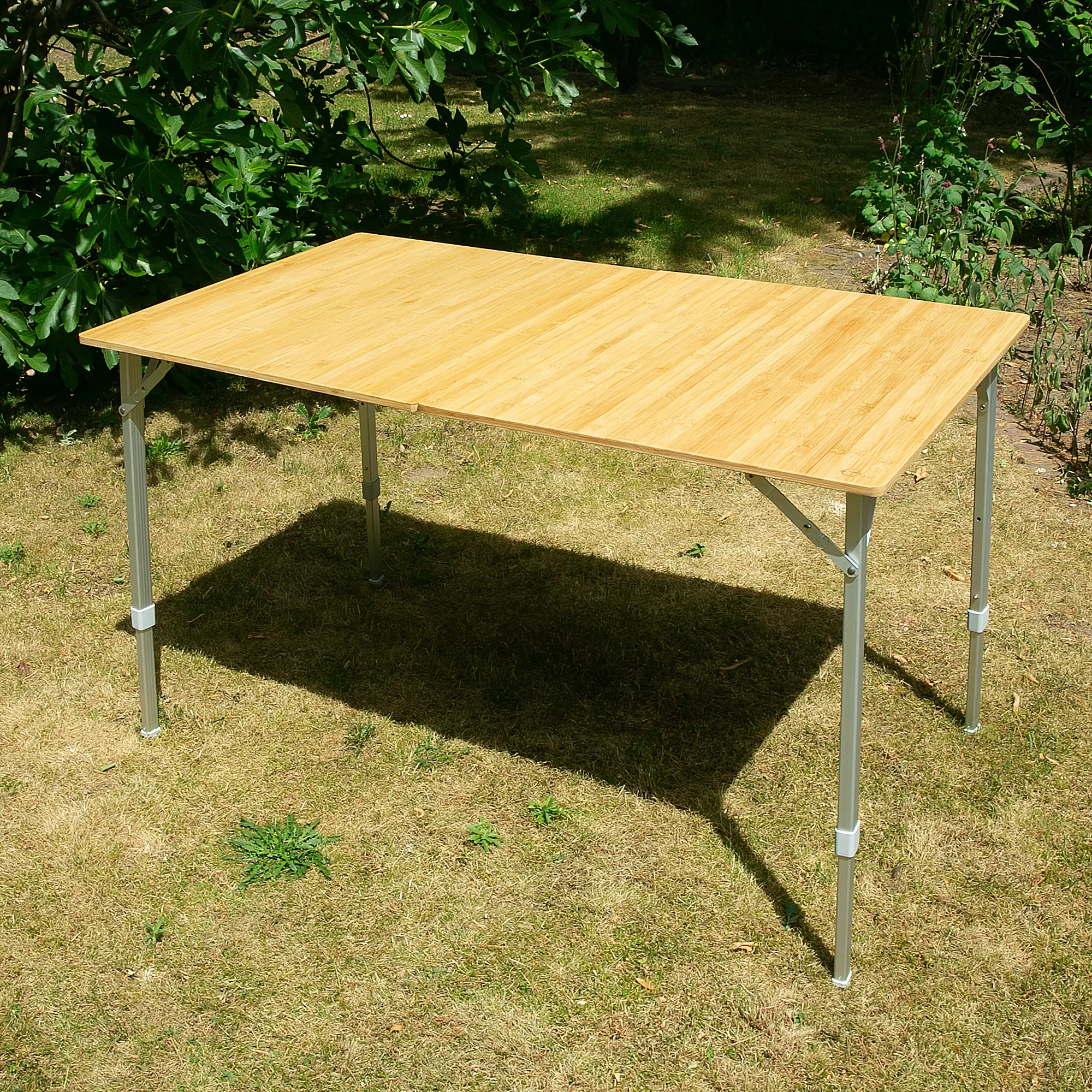Bambus Campingtisch your GEAR Portofino XL für 6 Personen, rechteckig, 120x70 cm, klappbar, höhenverstellbare Alu-Teleskopbeine, stabile Konstruktion, Outdoor-Einsatz auf Rasen im Garten.