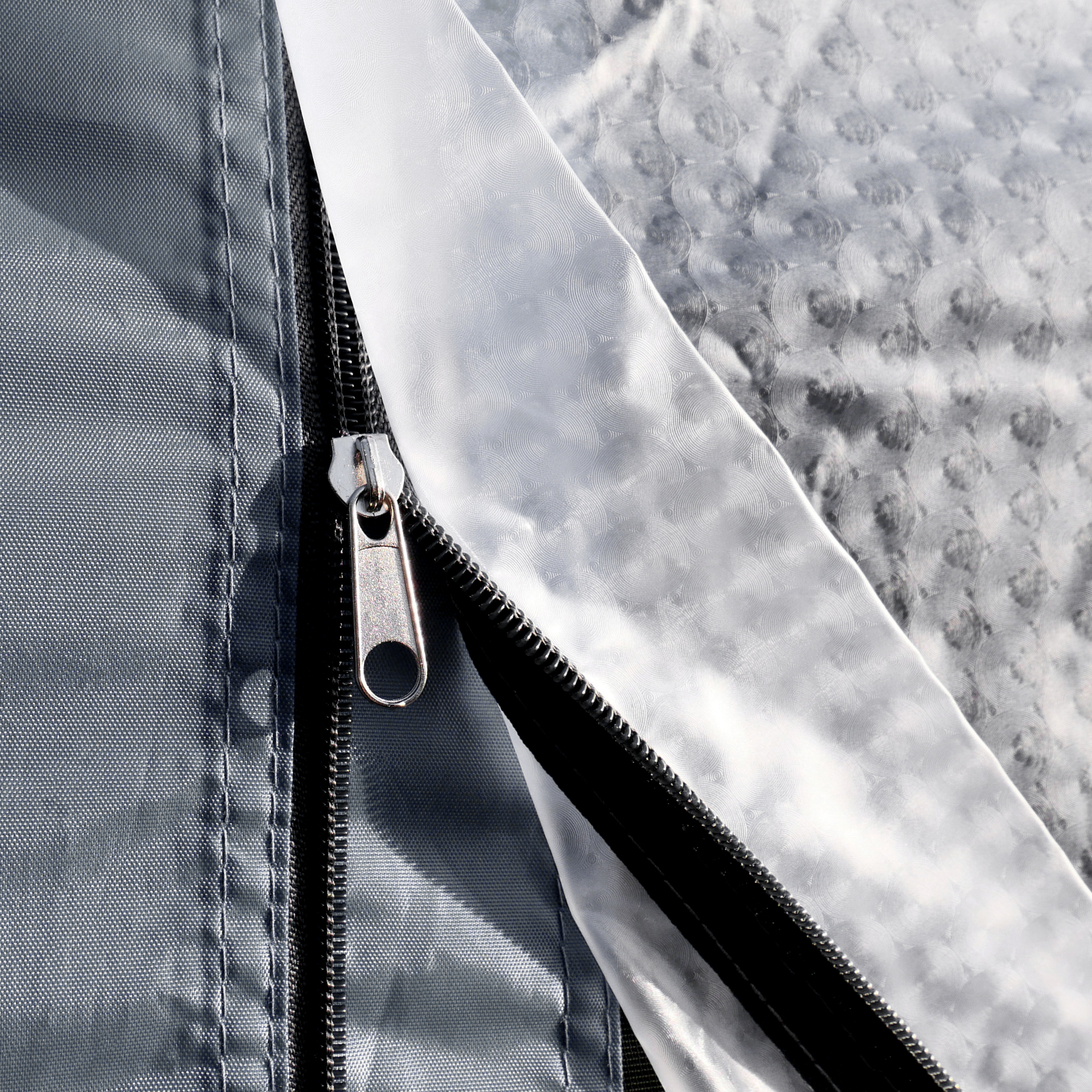 Gros plan sur une fermeture éclair métallique et couture d’un tissu gris imperméable du your GEAR Venecia – tente arrière pour caravane avec revêtement argenté réfléchissant et jointure pour bâche de sol incluse.