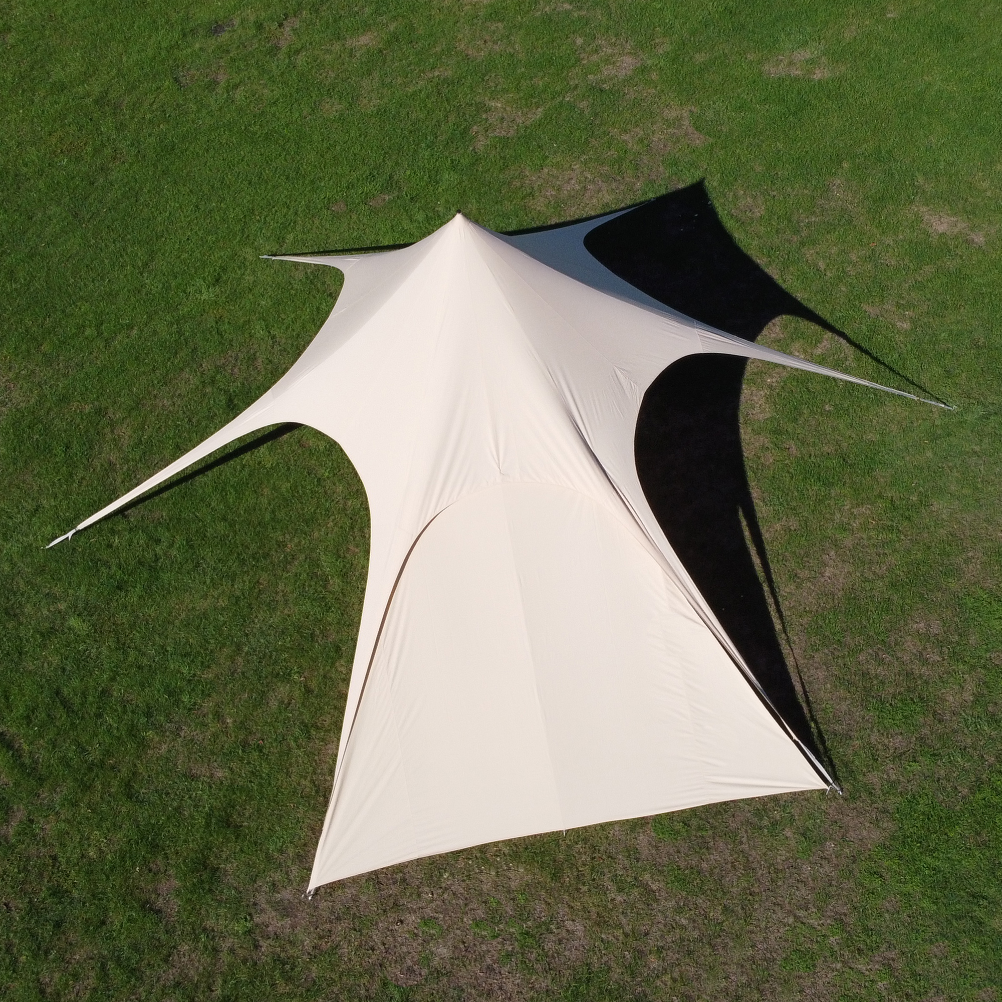 Beige your GEAR Sonora Sidewall for Sonora 10 pavilion, made from breathable cotton blend, shown attached to a large star-shaped sunshade, providing extra shade and weather protection on green grass.