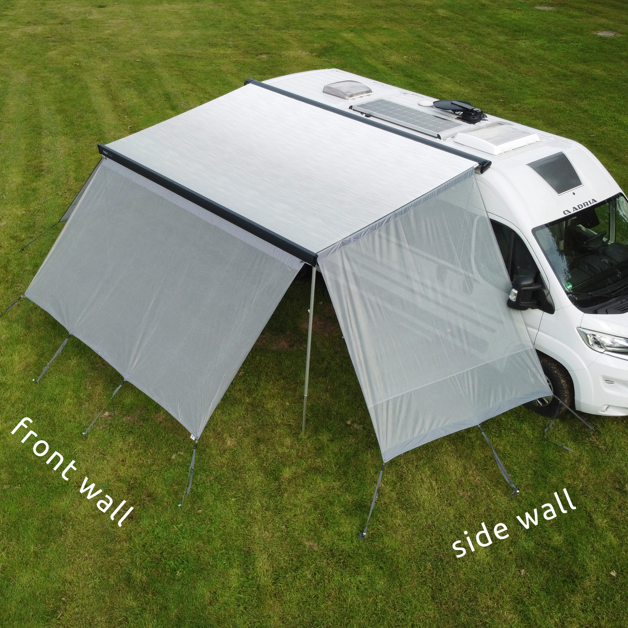 your GEAR Capri Side Blocker Set: two wind-permeable side panels mounted on a campervan awning, providing sun, wind, and privacy protection; shown attached to a white motorhome with grass background.