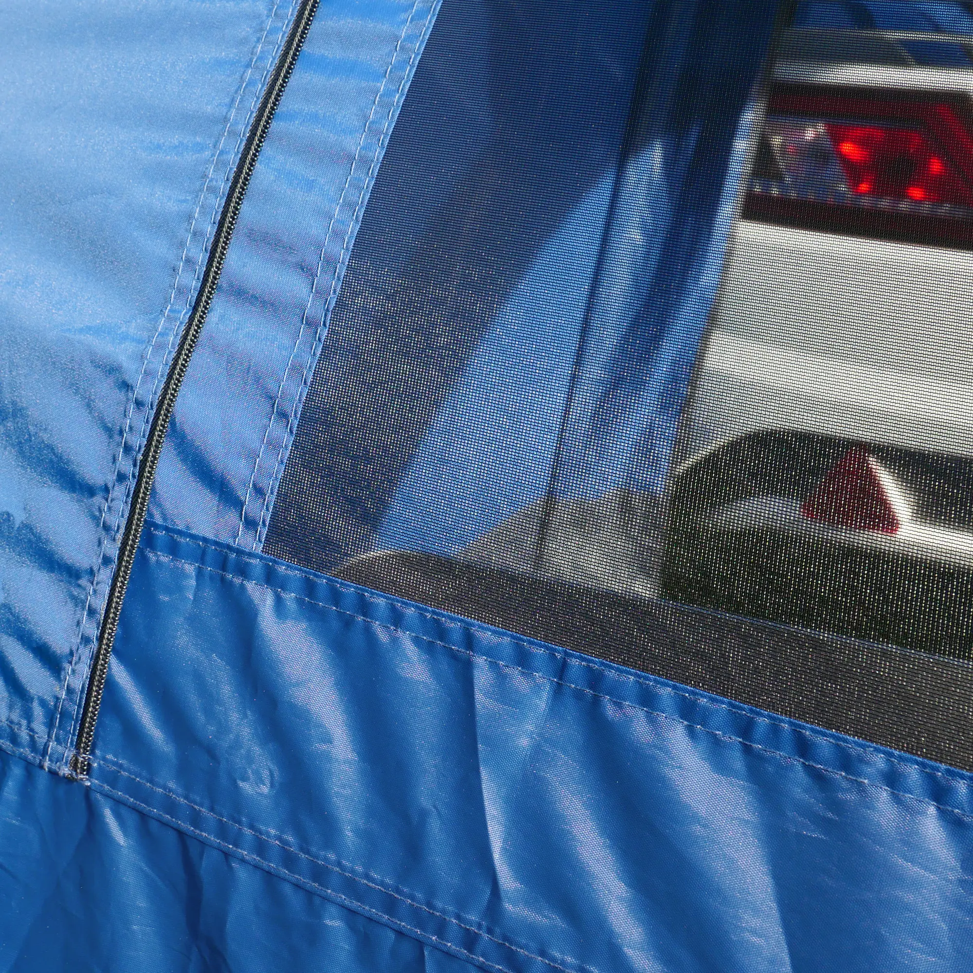 Detalle de la tela azul y ventana de malla del your GEAR Venecia, un avancé trasero para caravana, ideal como tienda de cocina o para equipos, con cremallera y costuras reforzadas, acoplado a un vehículo.