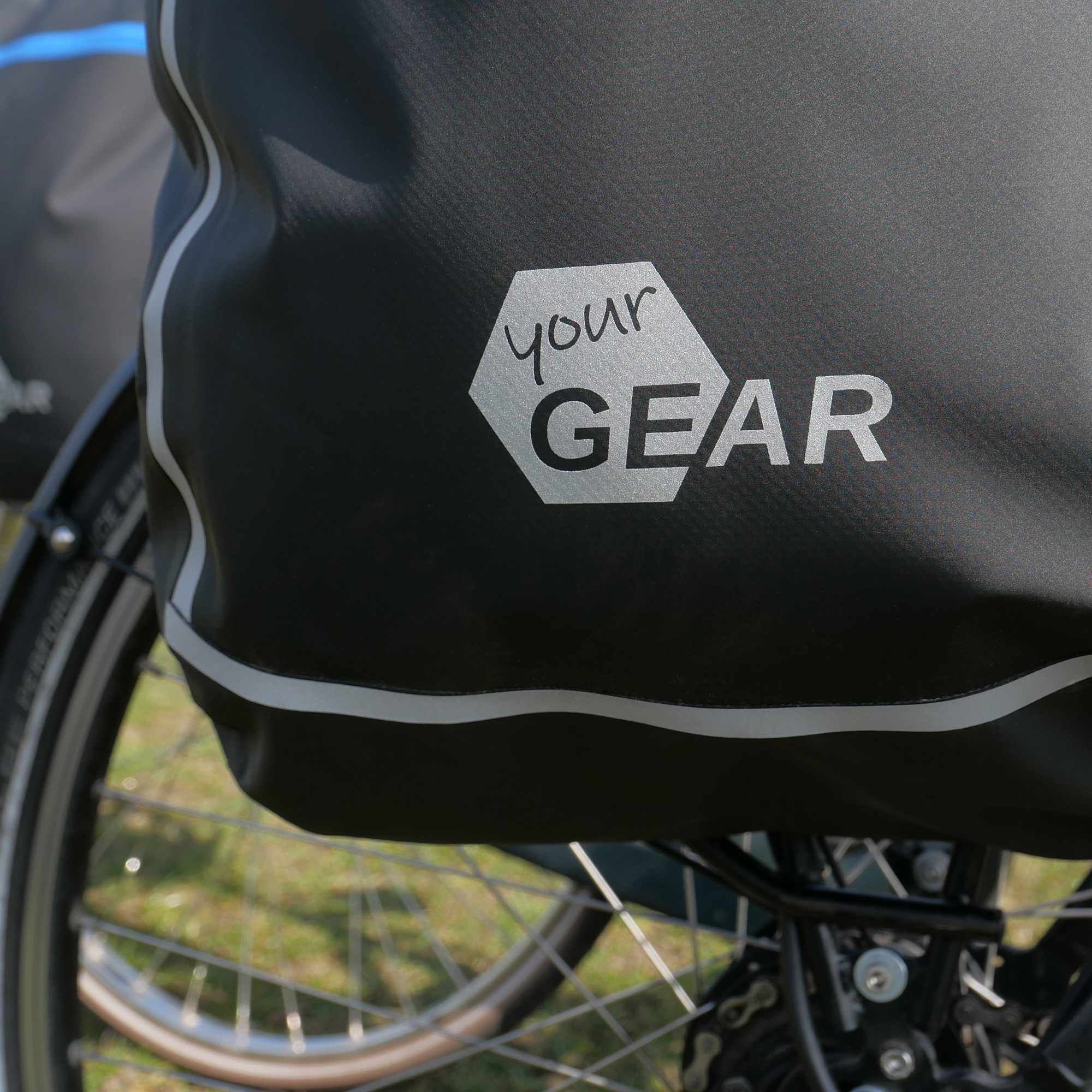 yourGEAR Arco 19 L waterproof 3-in-1 bike pannier attached to a bicycle rack, featuring reflective details and a visible yourGEAR logo. Suitable as a pannier, backpack, or laptop messenger bag.