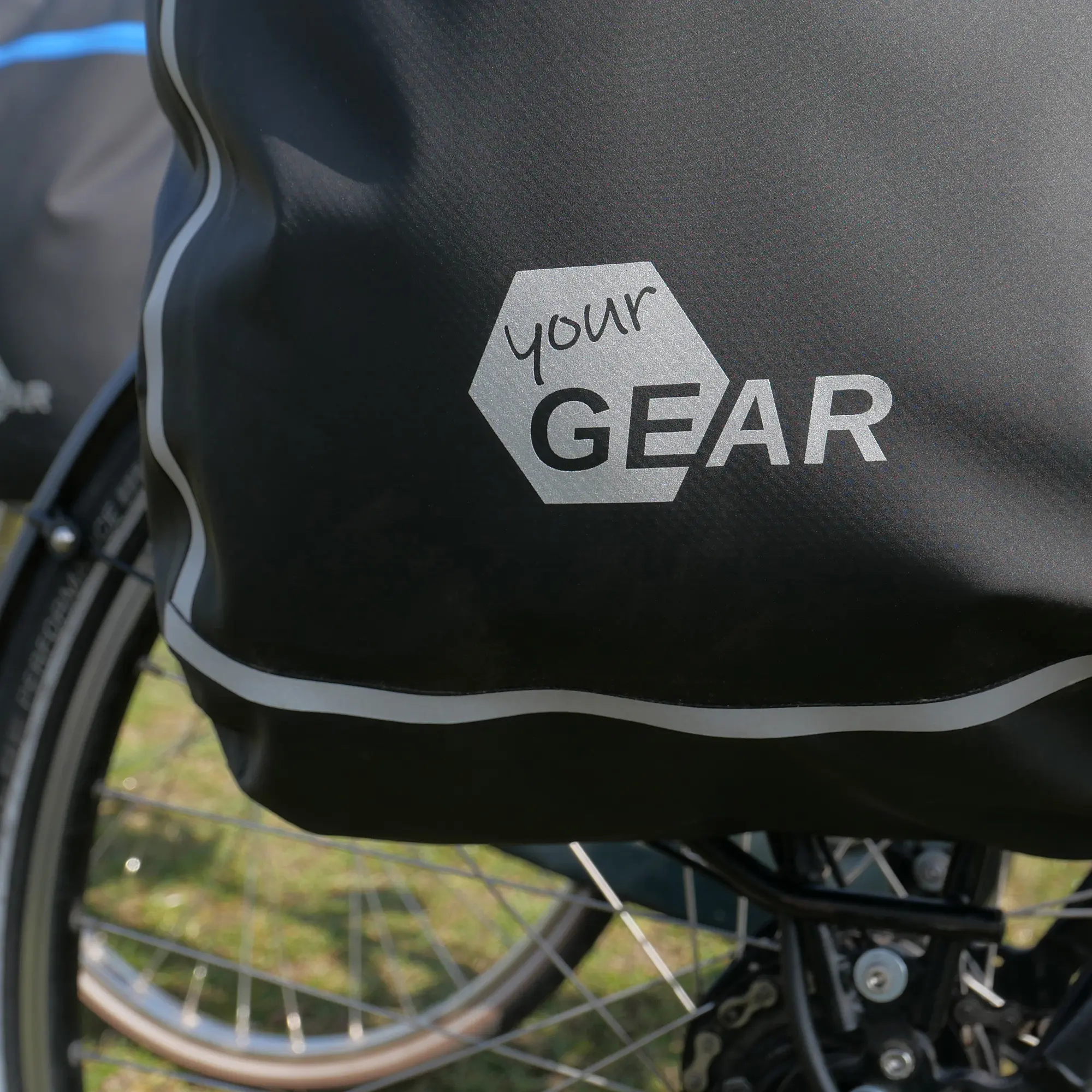 yourGEAR Arco 19 L waterproof 3-in-1 bike pannier attached to a bicycle rack, featuring reflective details and a visible yourGEAR logo. Suitable as a pannier, backpack, or laptop messenger bag.