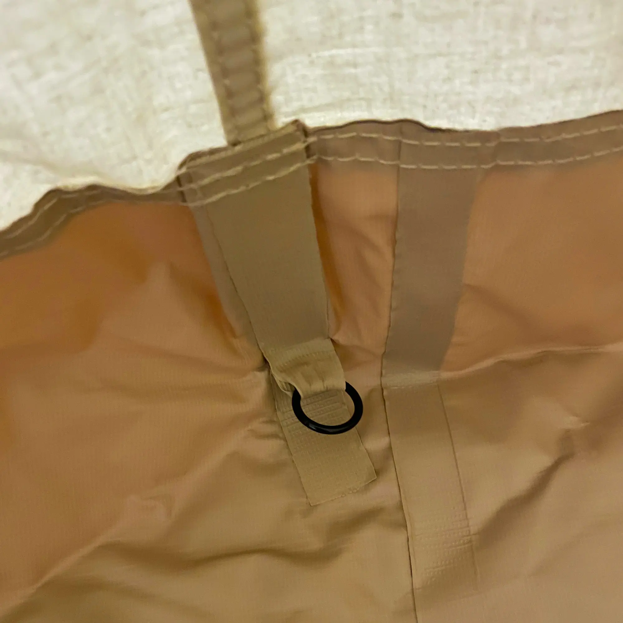 Détail intérieur du your GEAR Zelt Desert 8 Pro UV50+ : tissu beige en coton-mixte, couture renforcée et boucle d’attache sur le sol en bâche fixée, typique d’un tipi familial avec protection contre les insectes.