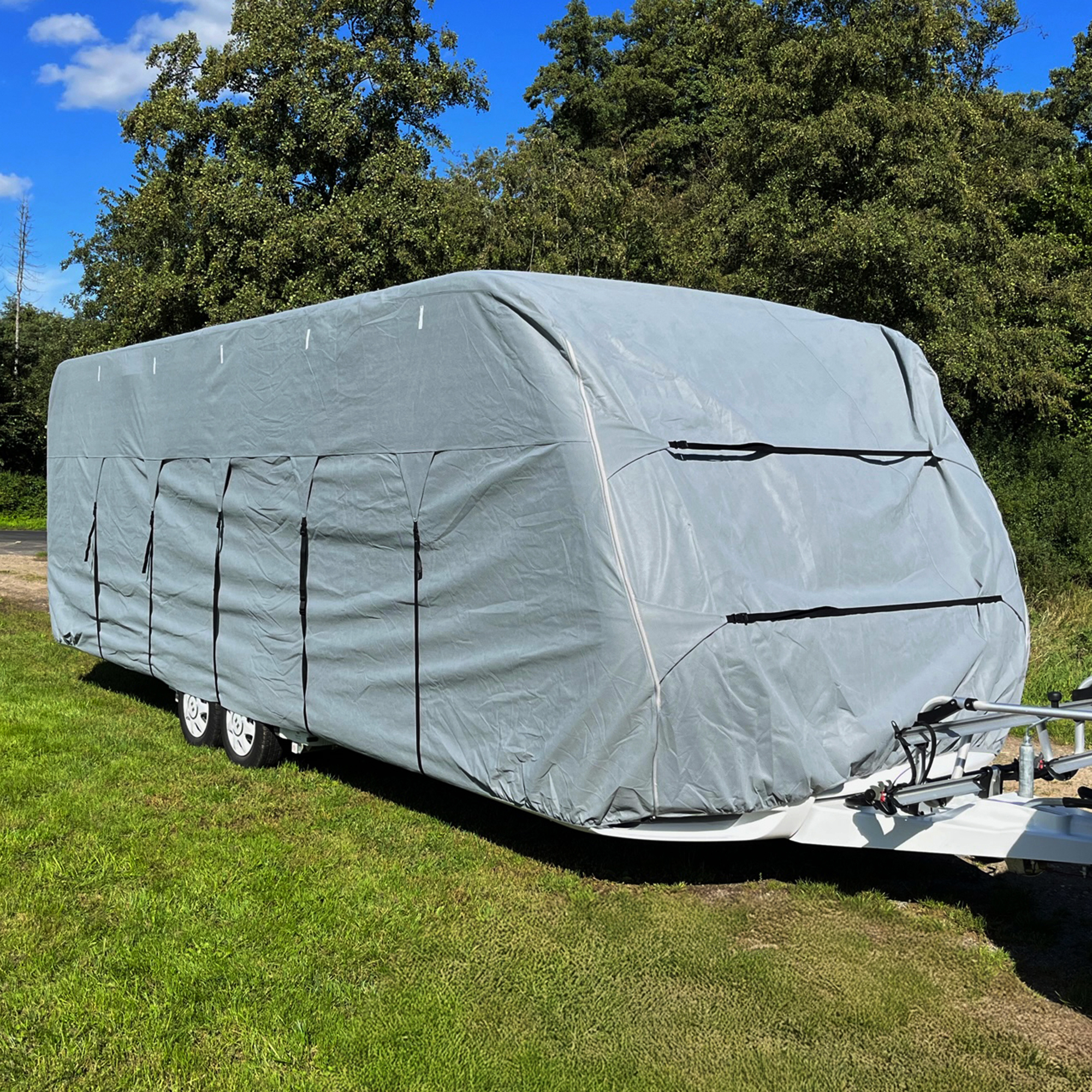 Graue your GEAR Wohnwagenabdeckung Bonito 670-710 aus vierlagigem Material, passend für Wohnwagen mit 670–710 cm Länge und 230–250 cm Breite, inklusive Deichselabdeckung, mit schwarzen Gurten befestigt.