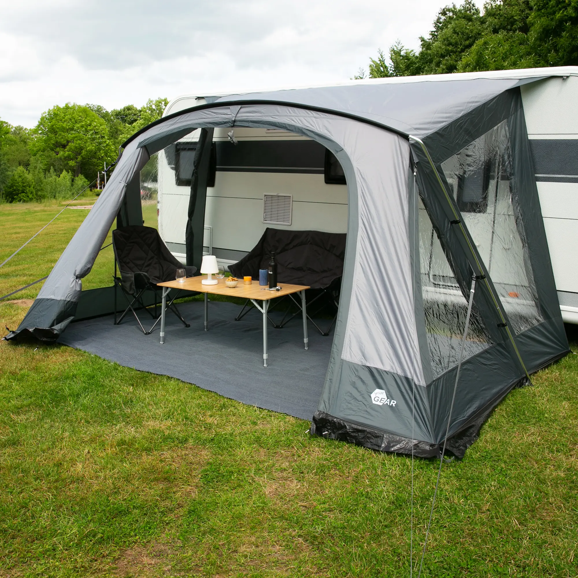 Spacious your GEAR Positano 400 caravan awning with four large windows, wide entrance forming a sun canopy, sturdy aluminum frame, and weatherproof Oxford fabric, set up beside a caravan on grass.