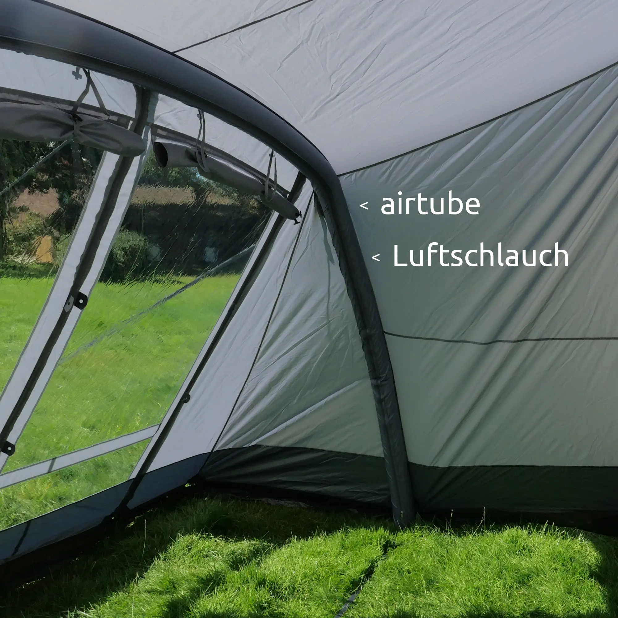 Interior view of the your GEAR Vicenza 350E AIR inflatable awning with visible airtube (Luftschlauch), large clear window panels, and sturdy single inflation air frame, set up on grassy ground.