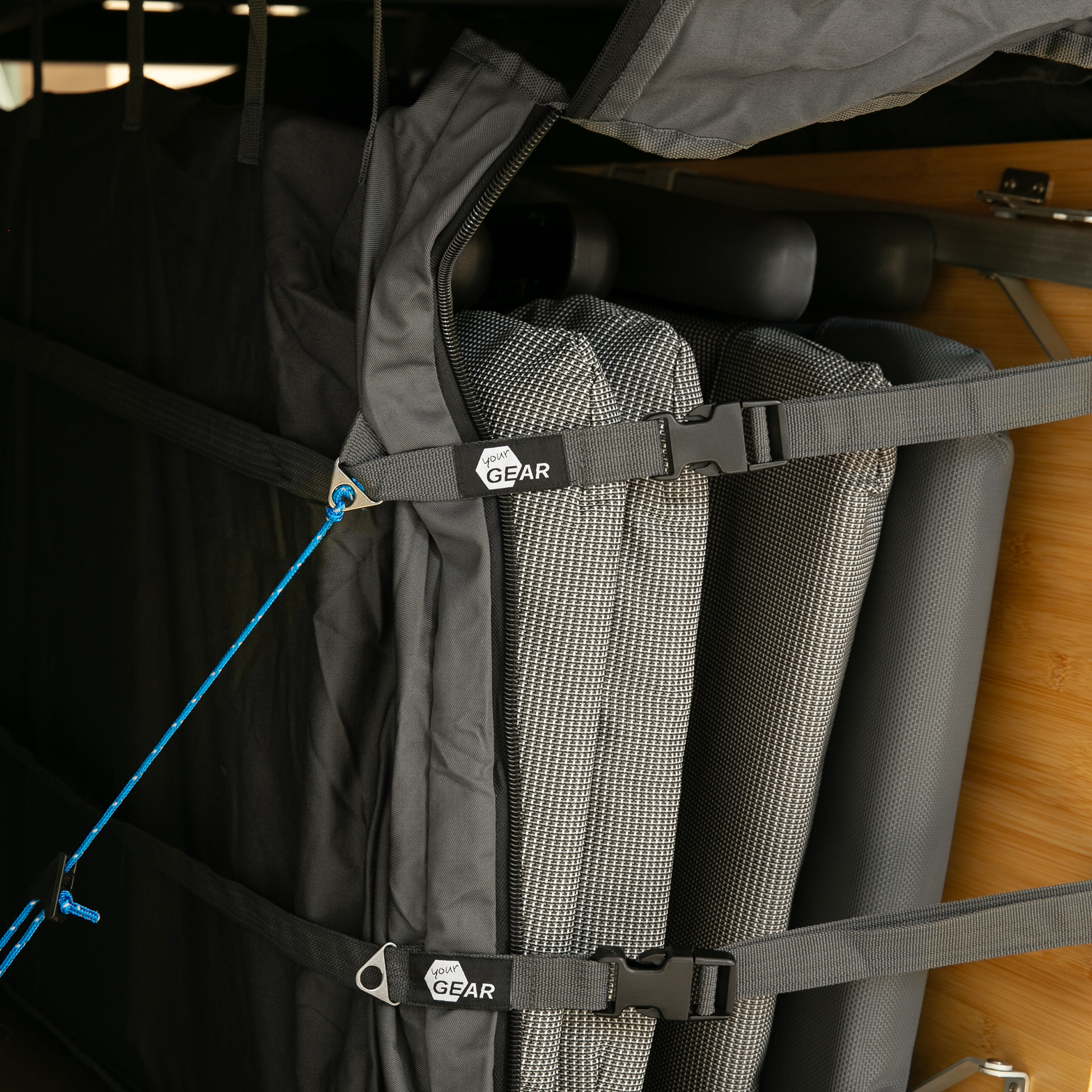 Sac de rangement your GEAR Bozen fixé verticalement dans une soute de van, maintenant des meubles de camping avec des sangles robustes et fermetures à clip, idéal pour organiser l’espace dans un camping-car.