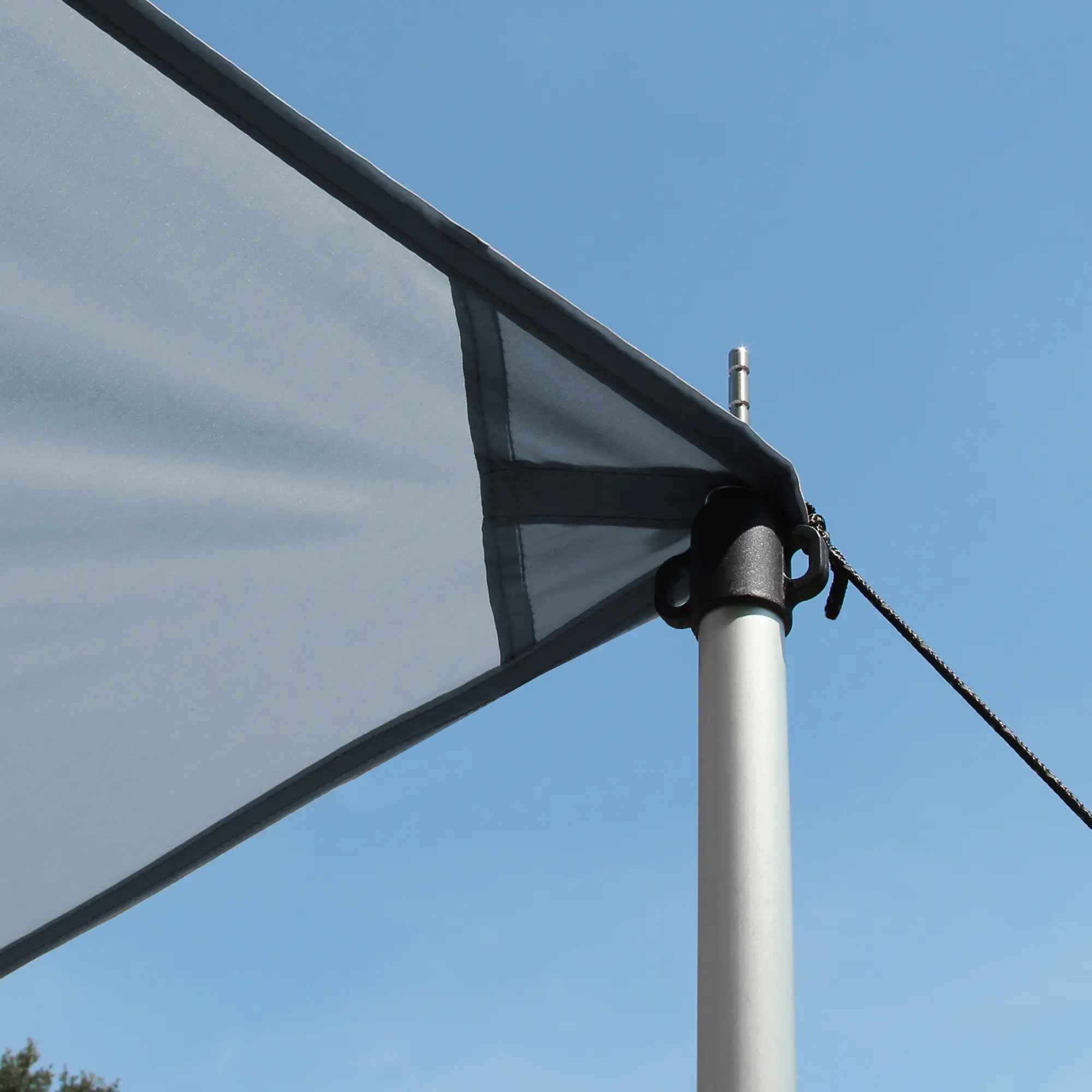 Auvent gris your GEAR pour caravane, dimensions 4,5 x 2,4 m, monté avec mât télescopique en aluminium et cordage, tissu résistant UV 50+, protection solaire et pluie, ciel bleu en arrière-plan.