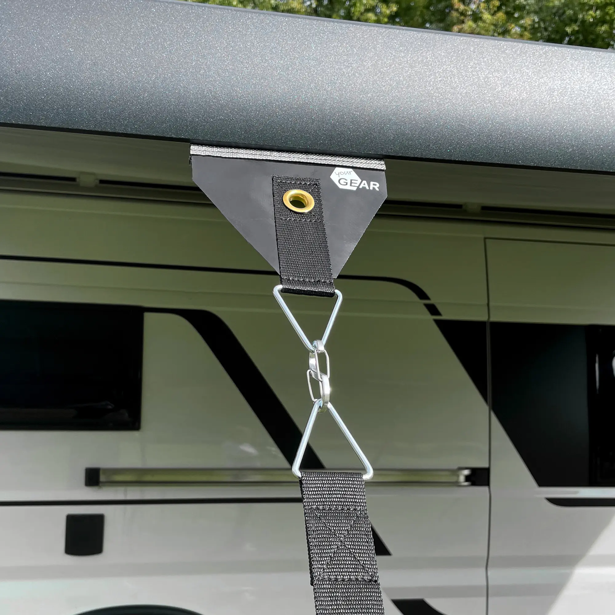 your GEAR Storm Set awning tie-down kit attached to an awning, showing reinforced black strap with metal eyelet, carabiner hook, and durable materials for secure storm protection on camper vans.
