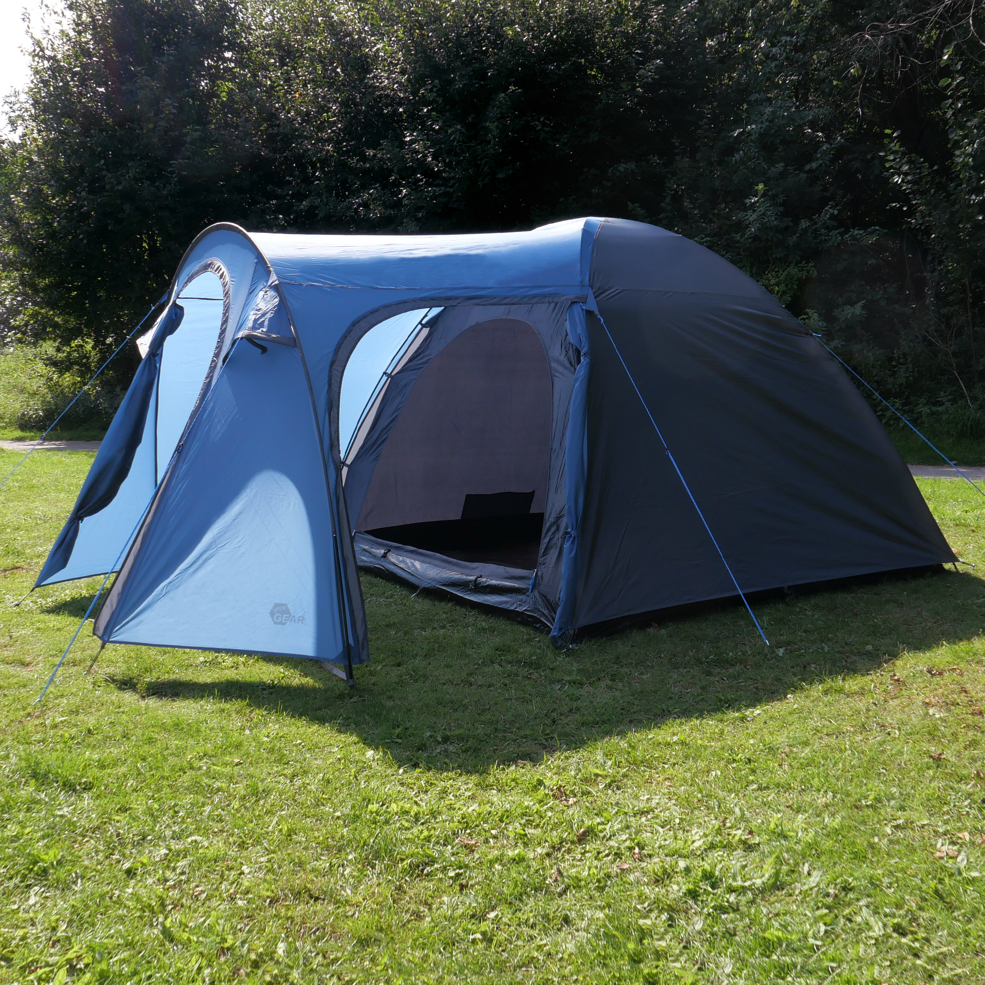your GEAR Cetona 4-person dome tent in blue and grey, with large vestibule, side entrance, standing height, and two doors, set up on grass; ideal for family camping and outdoor activities.