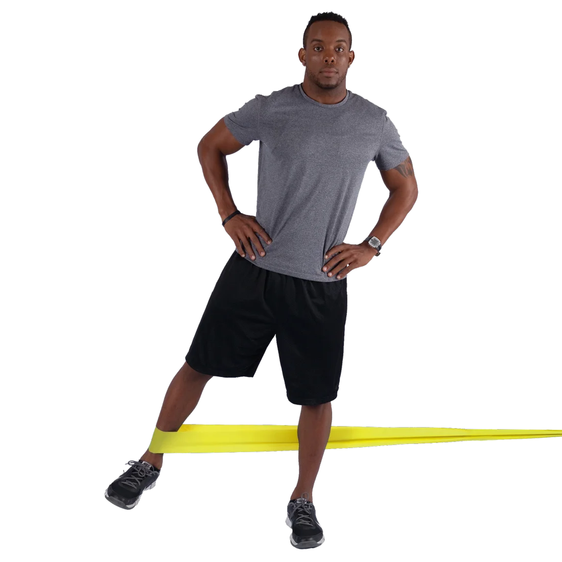 Man exercising with a yellow Spirit Fitness Band 183x10 cm, demonstrating resistance training; latex-free band stretched around legs for lower body workout; suitable for strength, rehab, and flexibility exercises.