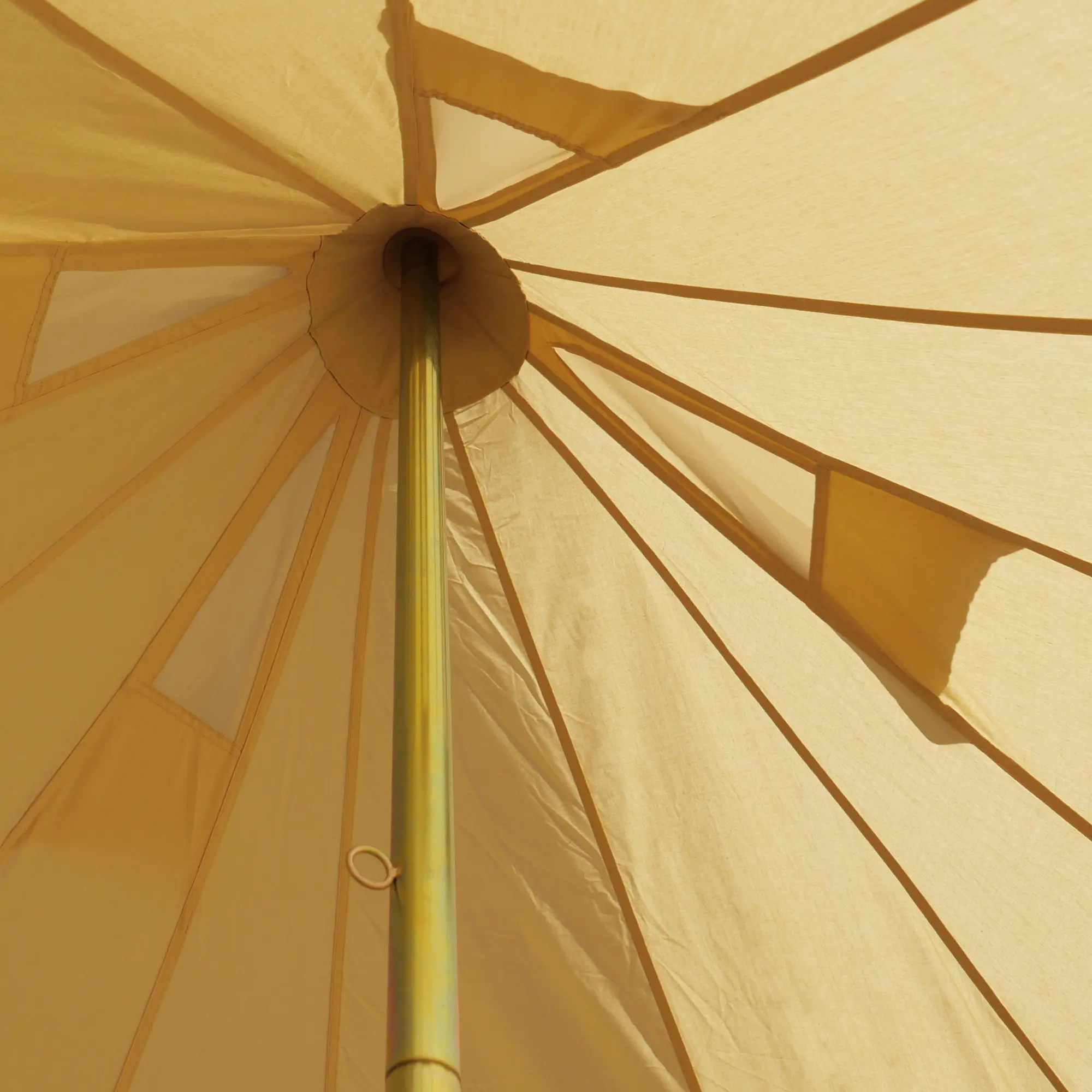 Vista interior del yourGEAR Zelt Desert 10 Pro, mostrando la estructura central y el techo de lona beige con paneles de ventilación, ideal para camping familiar. Detalle del mástil y costuras del tejido de algodón.