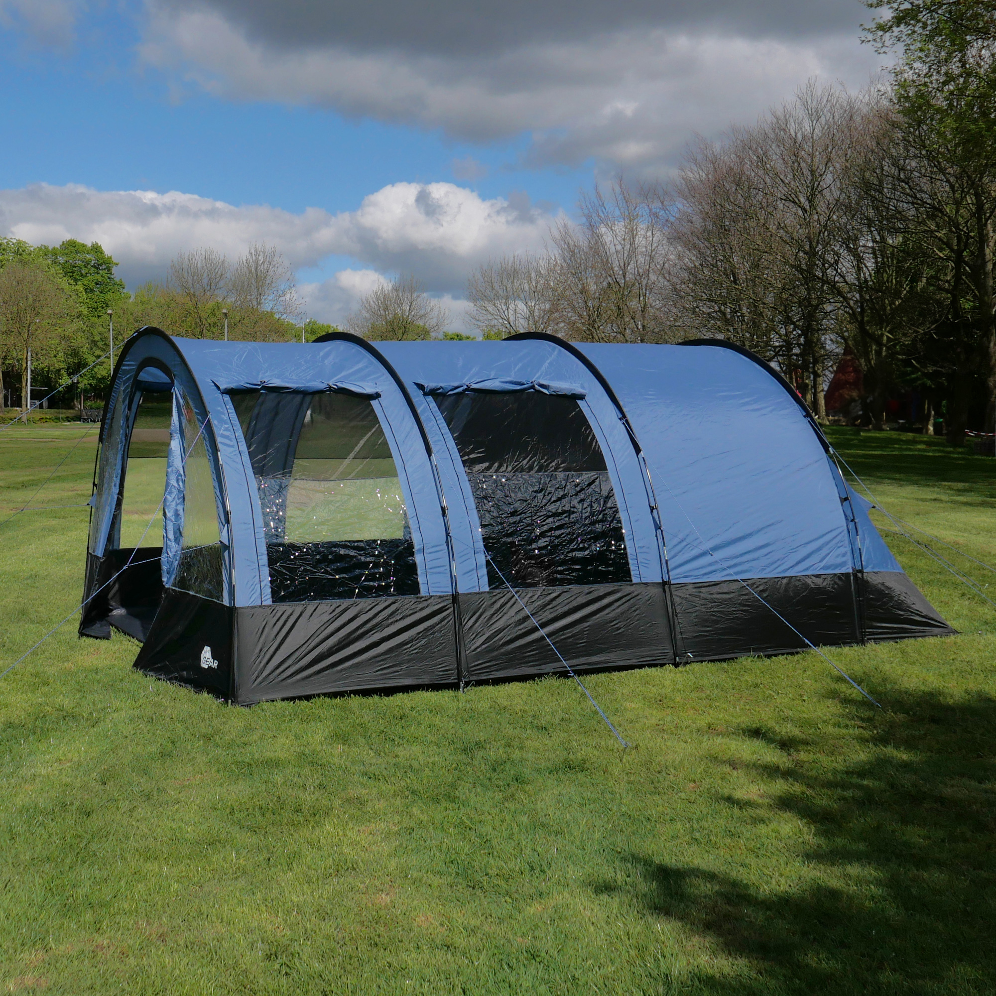 Tente tunnel familiale your GEAR Mistral pour 6 personnes, 490x325x195 cm, couleur bleue avec grandes fenêtres transparentes, ventilation latérale, installée sur pelouse, idéale pour le camping en groupe.