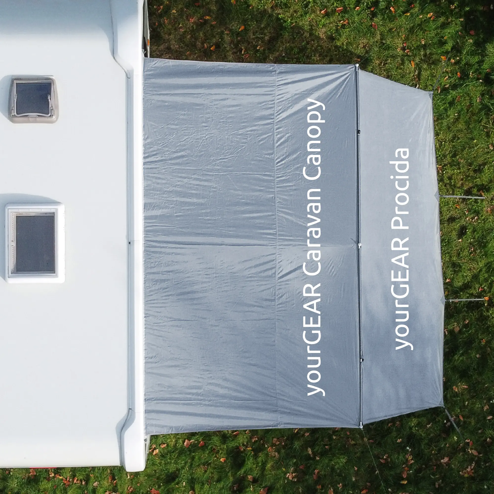 Overhead view of your GEAR Procida 300x200 cm sun protection front wall attached to a caravan canopy, showing the grey fabric, labeled sections, and setup with poles on grassy ground. Ideal for caravan sun and privacy.