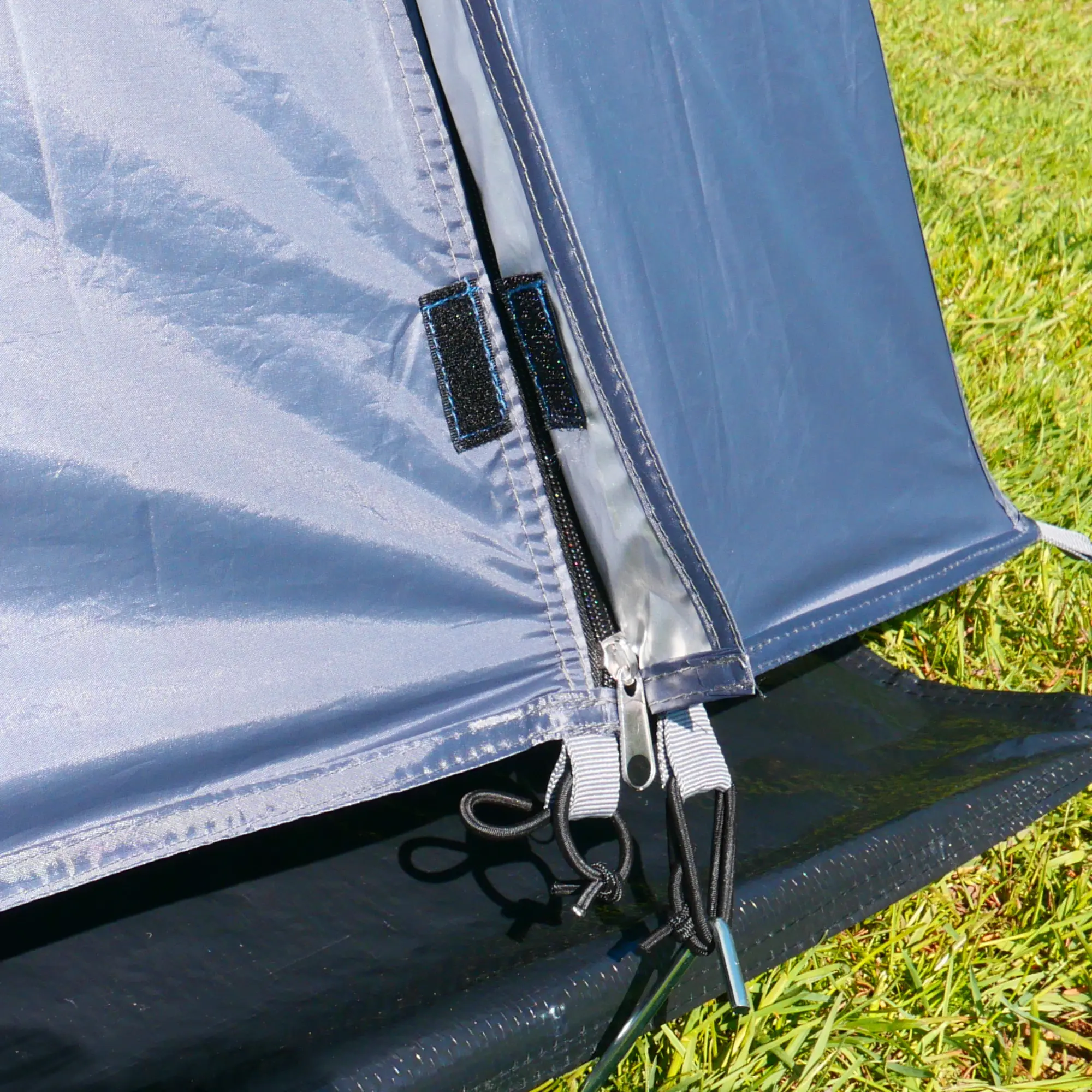 Vorderwand mit Reißverschluss und Zeltboden des yourGEAR Panarea 320 Zubehörsets, aus robustem 150D Oxford Polyester mit ALU/PU-Beschichtung, auf einer Wiese aufgebaut. Ideal für Busvorzelt und Mini Camper.