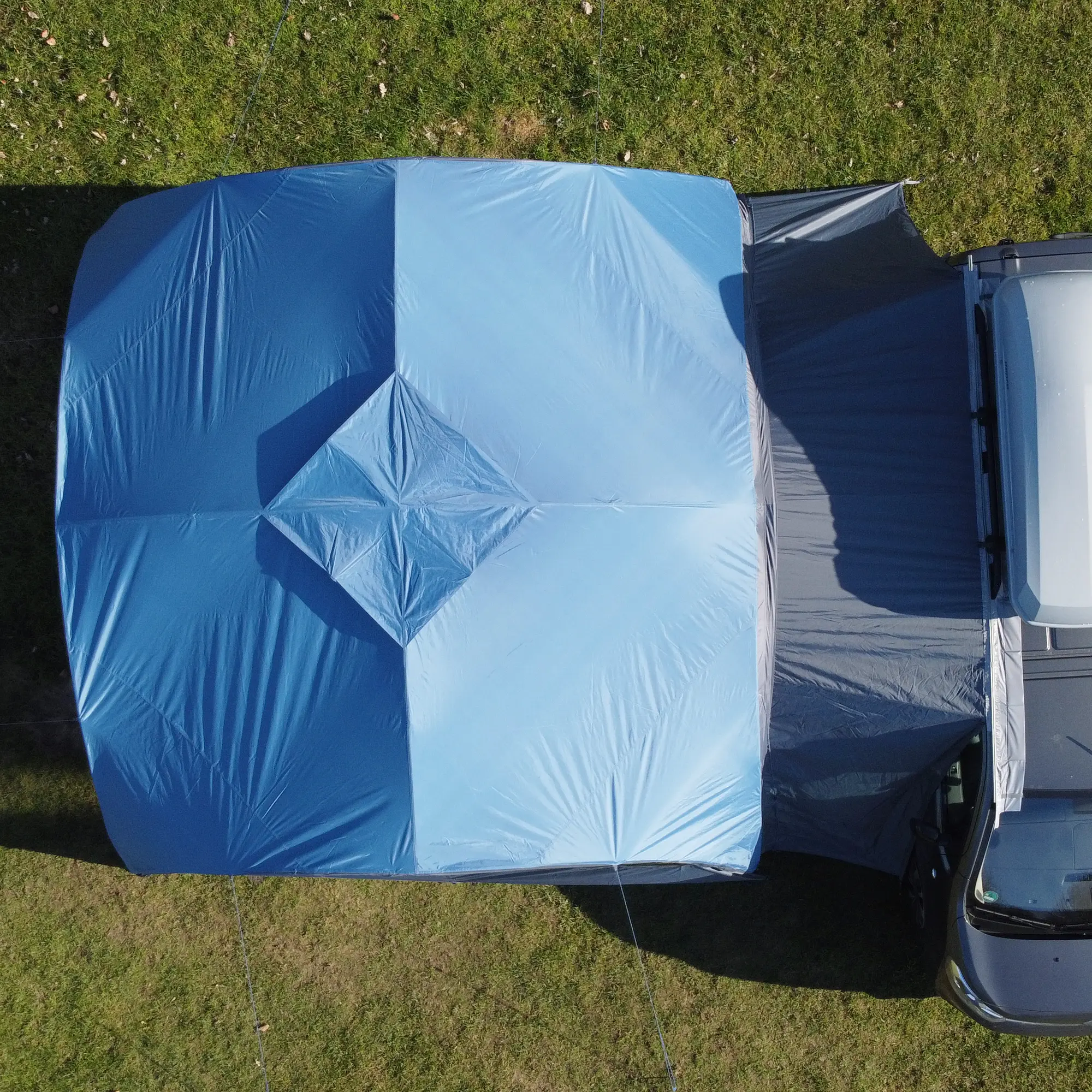 Top view of the your GEAR Bergamo 430 Bus Connector vehicle awning, showing the blue pavilion attached to a van via the grey connector tunnel, providing a weather-protected link for camping and outdoor events.