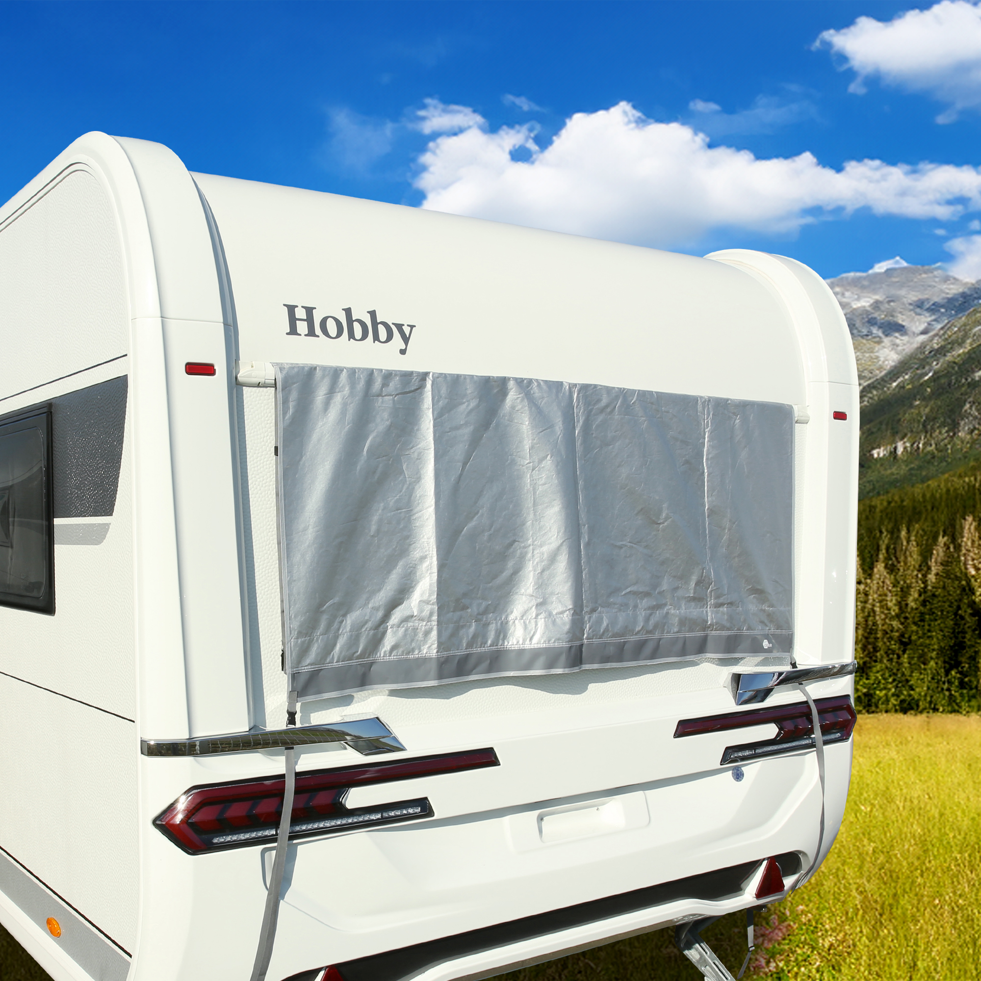 Silver your GEAR Padua window awning 140 x 70 cm with 7 mm piping, mounted on the rear window of a white caravan, provides UV 80+ sun protection; shown outdoors with a mountain landscape in the background.