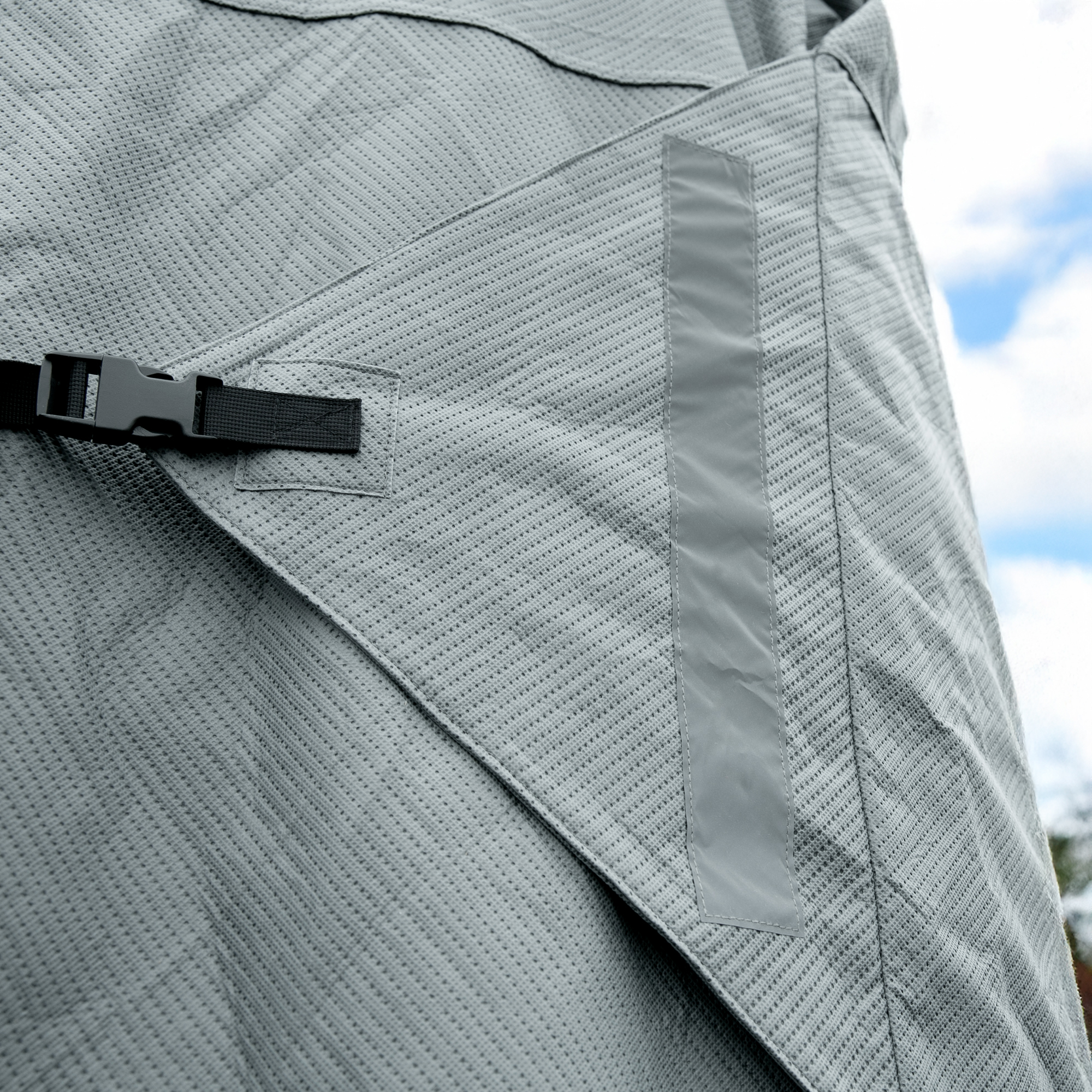 Detailansicht der your GEAR Naro L/XL Wohnwagenabdeckung aus grauem, vierlagigem Material mit atmungsaktiver Struktur, stabiler Naht, Verstärkungsstreifen und schwarzem Klickverschluss für Hobby beachy 420 und 450.