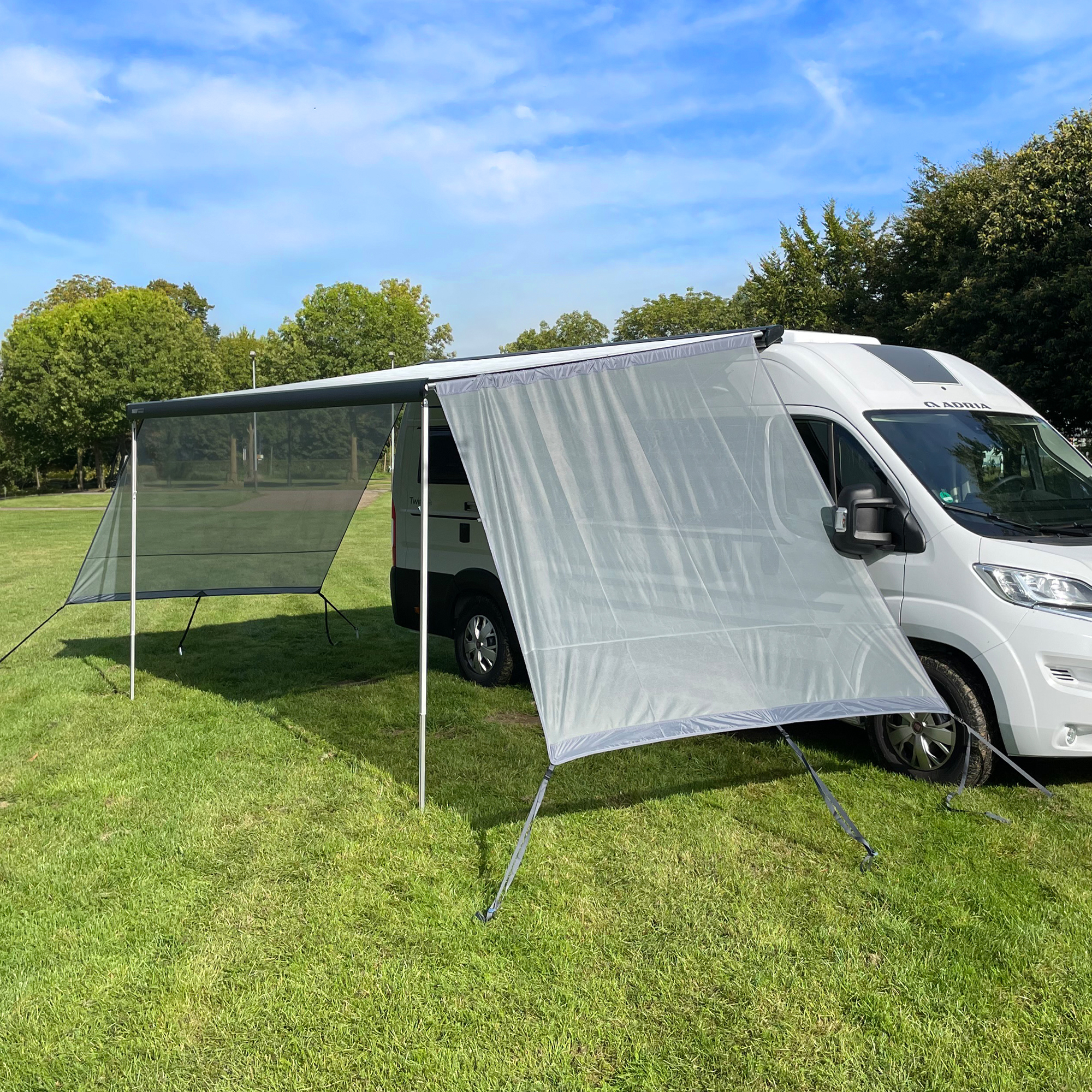 your GEAR Capri Side Blocker Set: Zwei winddurchlässige, graue Seitenwände als Sonnen- und Sichtschutz an einer Markise eines Wohnmobils montiert, geeignet für Campingbusse und Wohnwagen, Outdoor-Einsatz.
