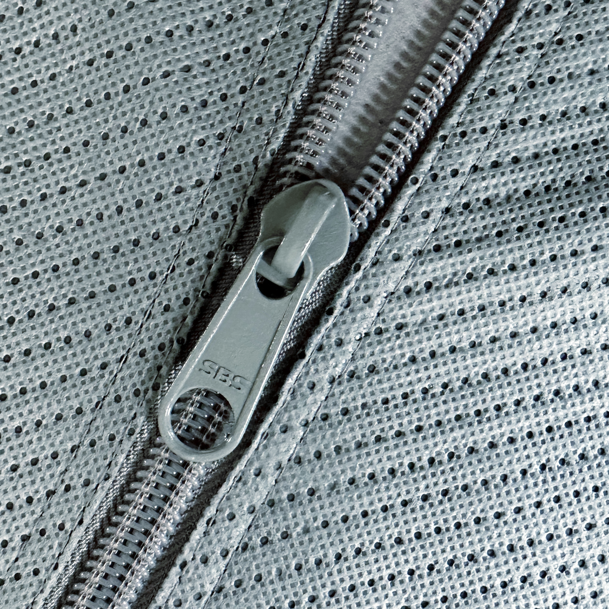 Close-up of the your GEAR Naro M caravan cover for Hobby beachy 360, showing a durable SBS zipper and breathable, four-layer grey polypropylene material with a textured, perforated surface.