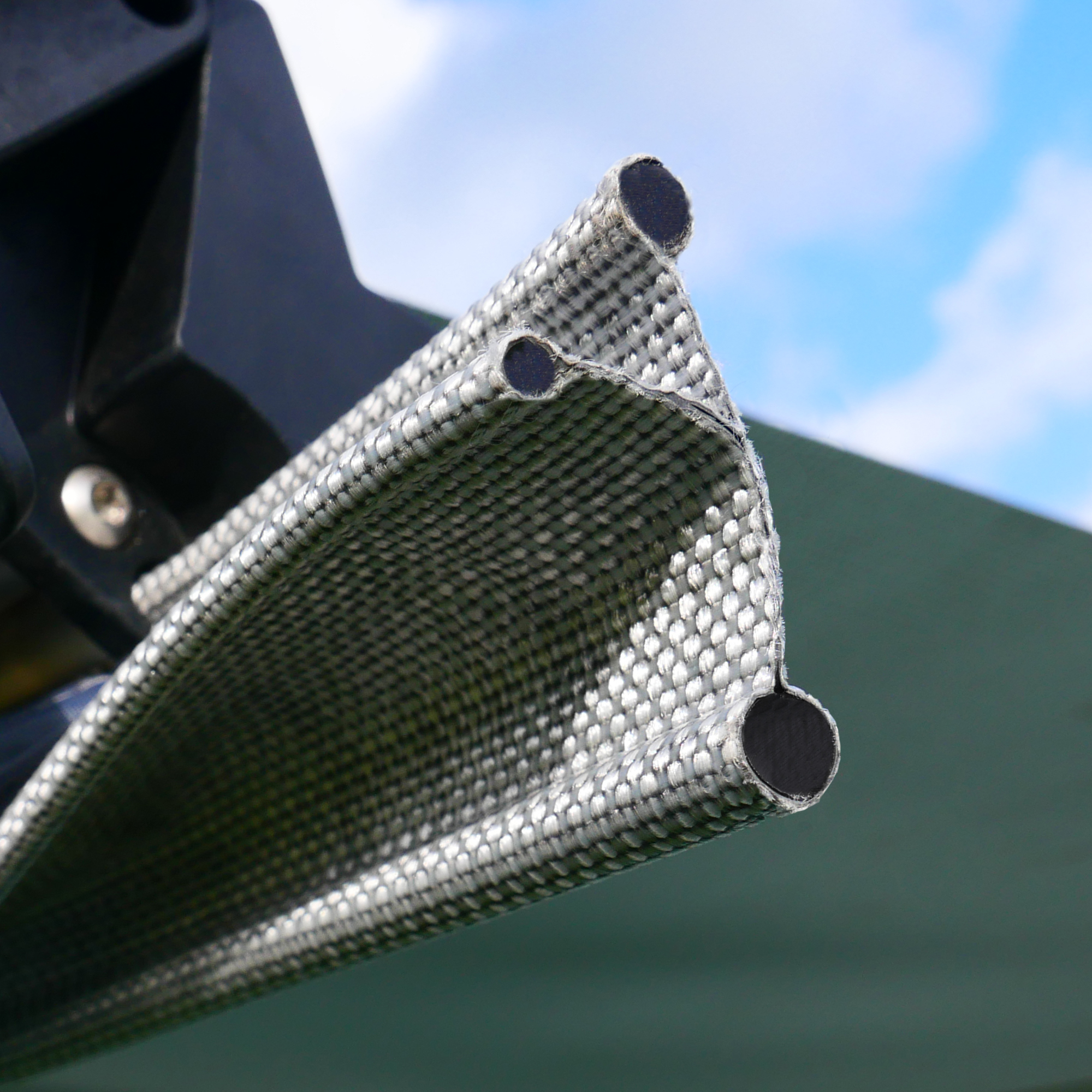 Dettaglio del tessuto rinforzato del your GEAR Parasol, tendalino da 260 x 260 cm per Bulli e camper, con canalina per asta e struttura resistente per bus e van da campeggio, sfondo cielo.