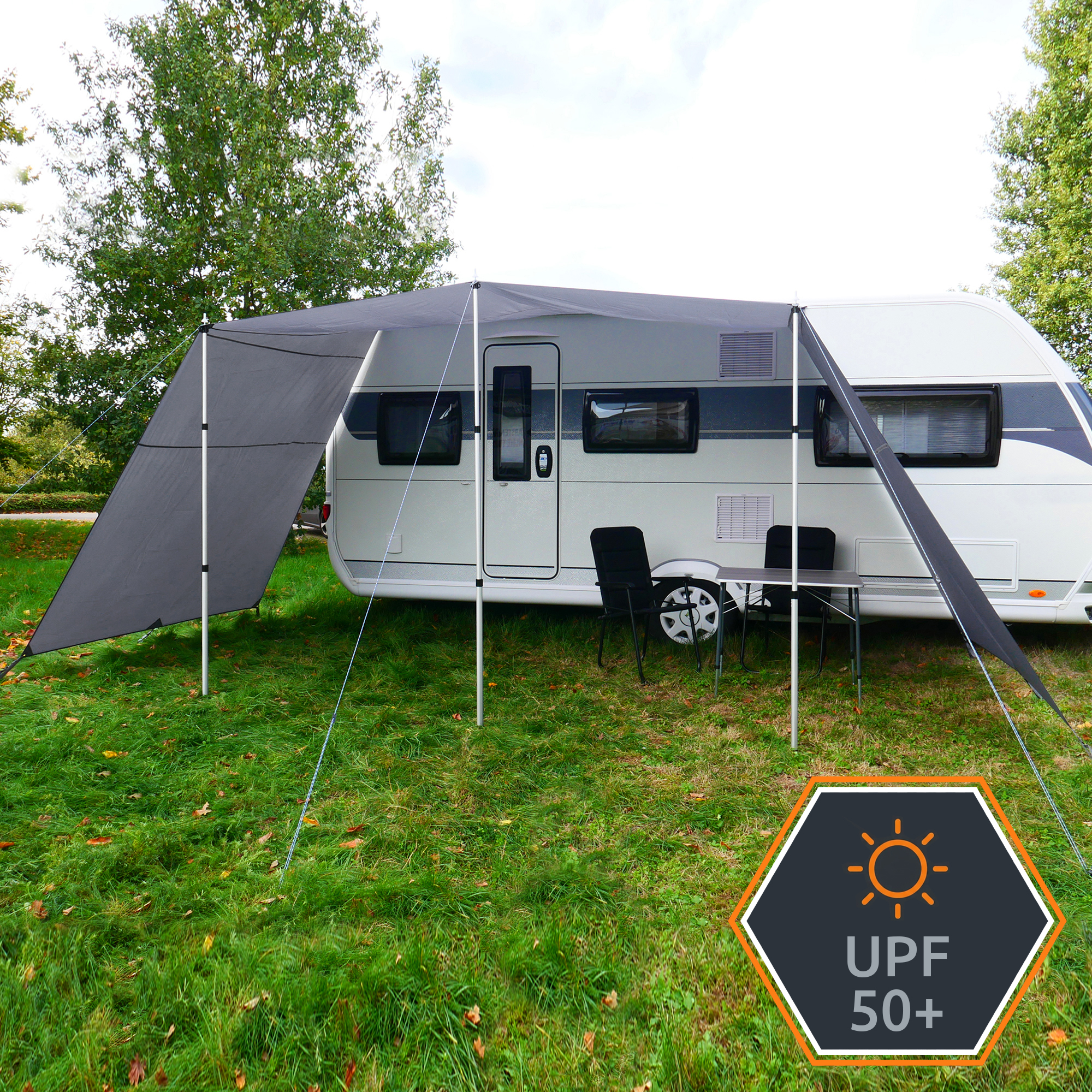 Toldo gris para caravana your GEAR Teramo 450 x 240 cm con paredes laterales, estructuras de aluminio telescópicas, instaldo como porche con sillas y mesa, protección solar UPF 50+ y cuerdas de anclaje visibles sobre césped.