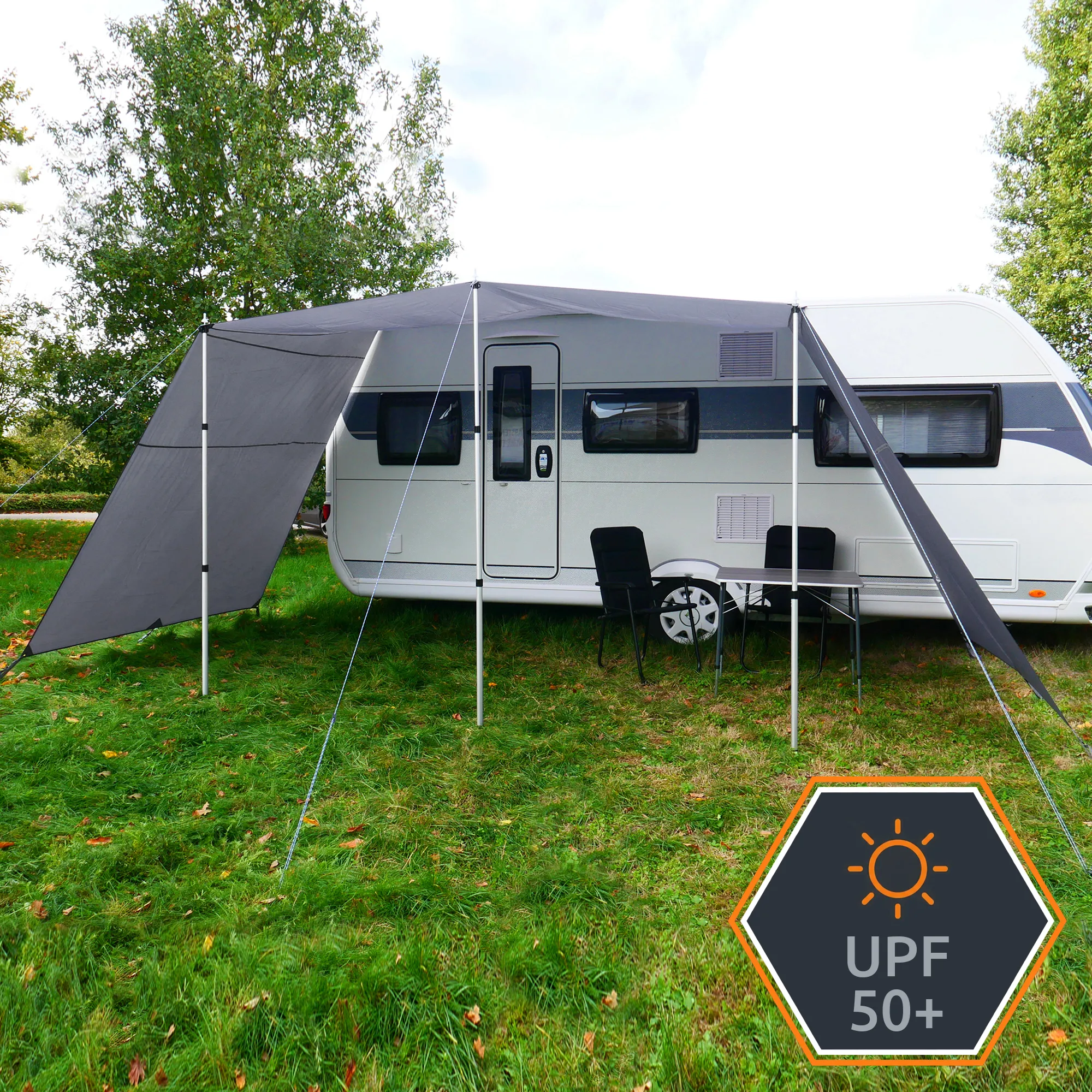 Sonnette grise your GEAR Teramo 450 x 240 cm fixée à une caravane, toit et parois latérales en tissu gris Cool Gray, armature en mâts télescopiques aluminium, haubans, espace ombragé avec table et chaises, protection solaire UPF 50+.