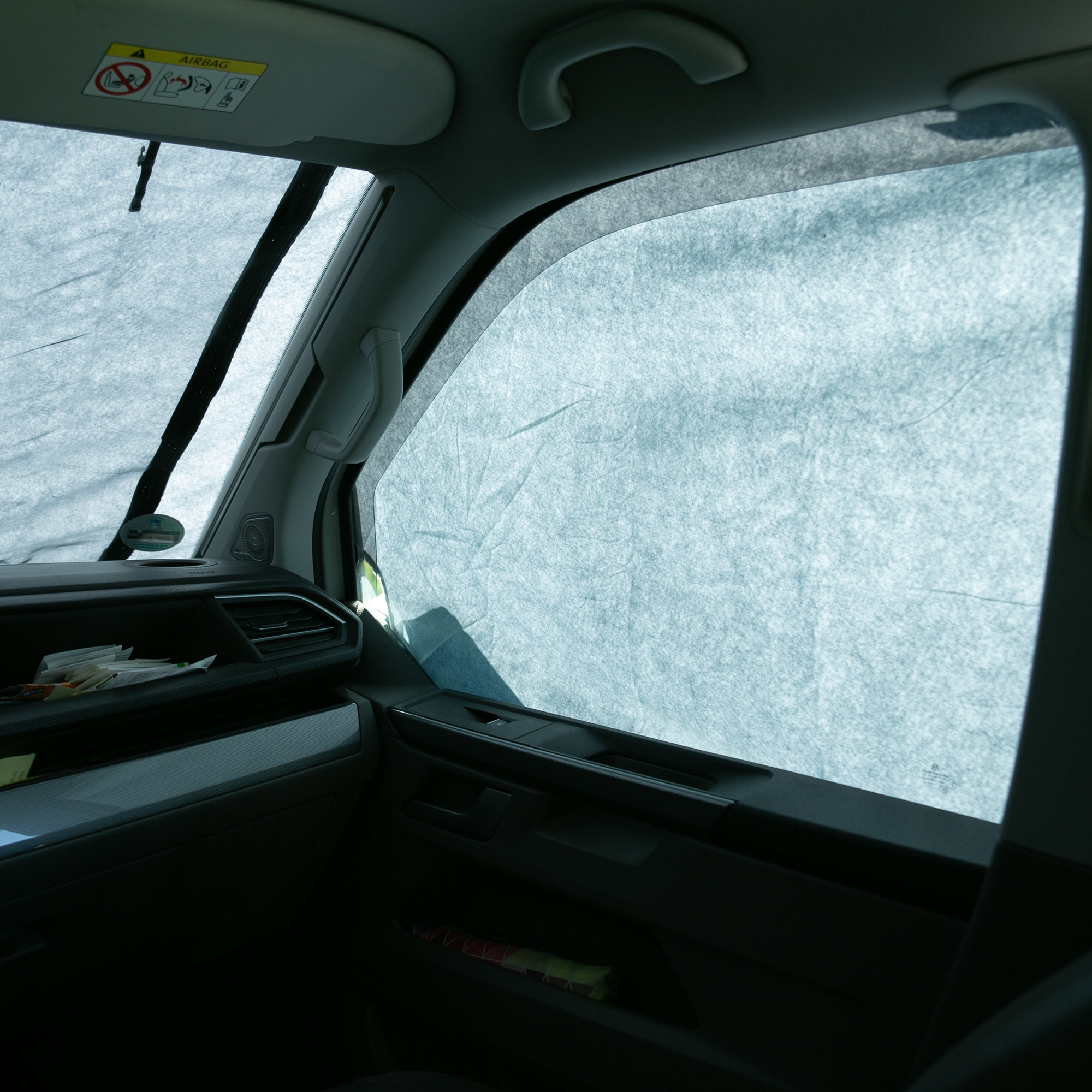 Sonnenschutzmatte your GEAR Sanremo Plus im VW T5/6/6.1 angebracht, schützt Fahrer- und Beifahrerfenster vor Sonne und Hitze, bietet Sichtschutz bei gleichzeitigem Durchblick nach außen.