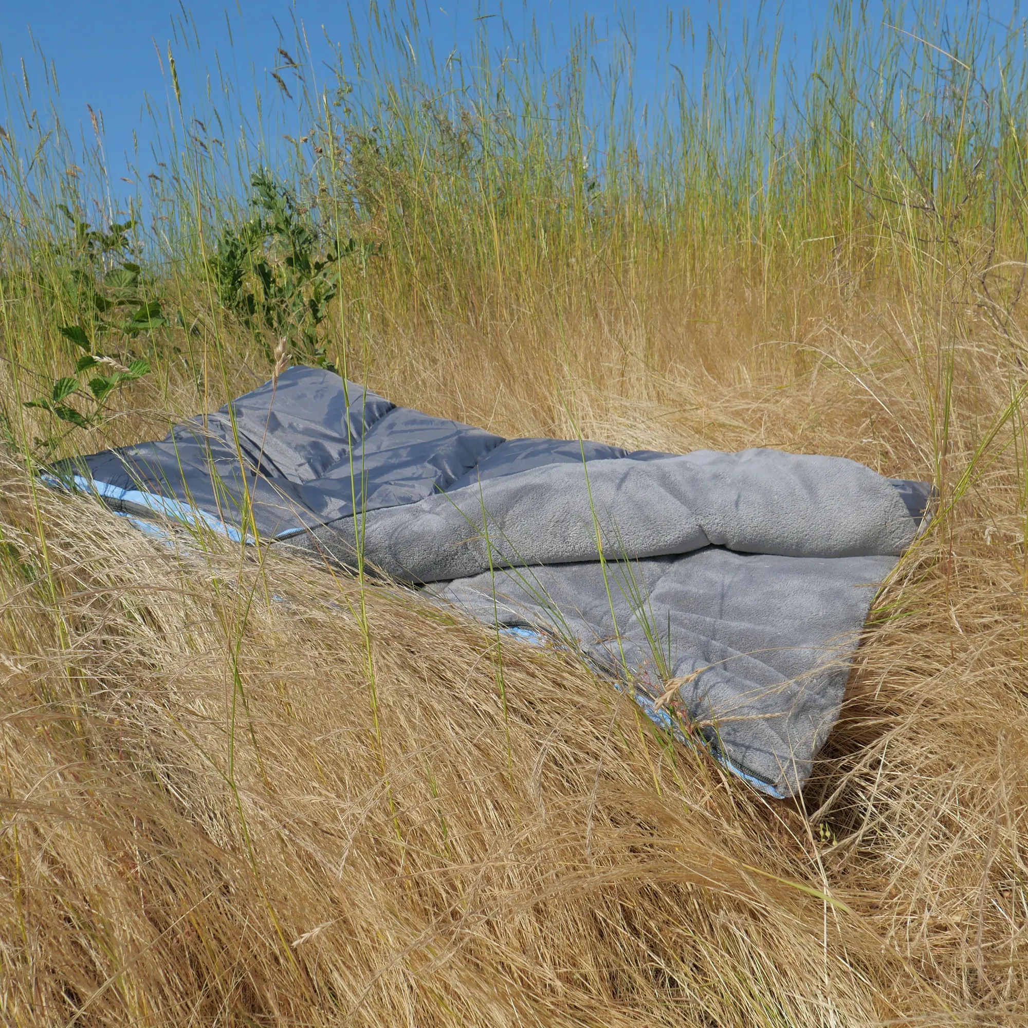 your GEAR Lodi 3-in-1 Hundeschlafsack aus grauer Mikrofaser, ausgebreitet auf trockenem Gras, ideal als Hundedecke, Schlafsack oder Handtuch für Camping und Outdoor, robust und waschbar.