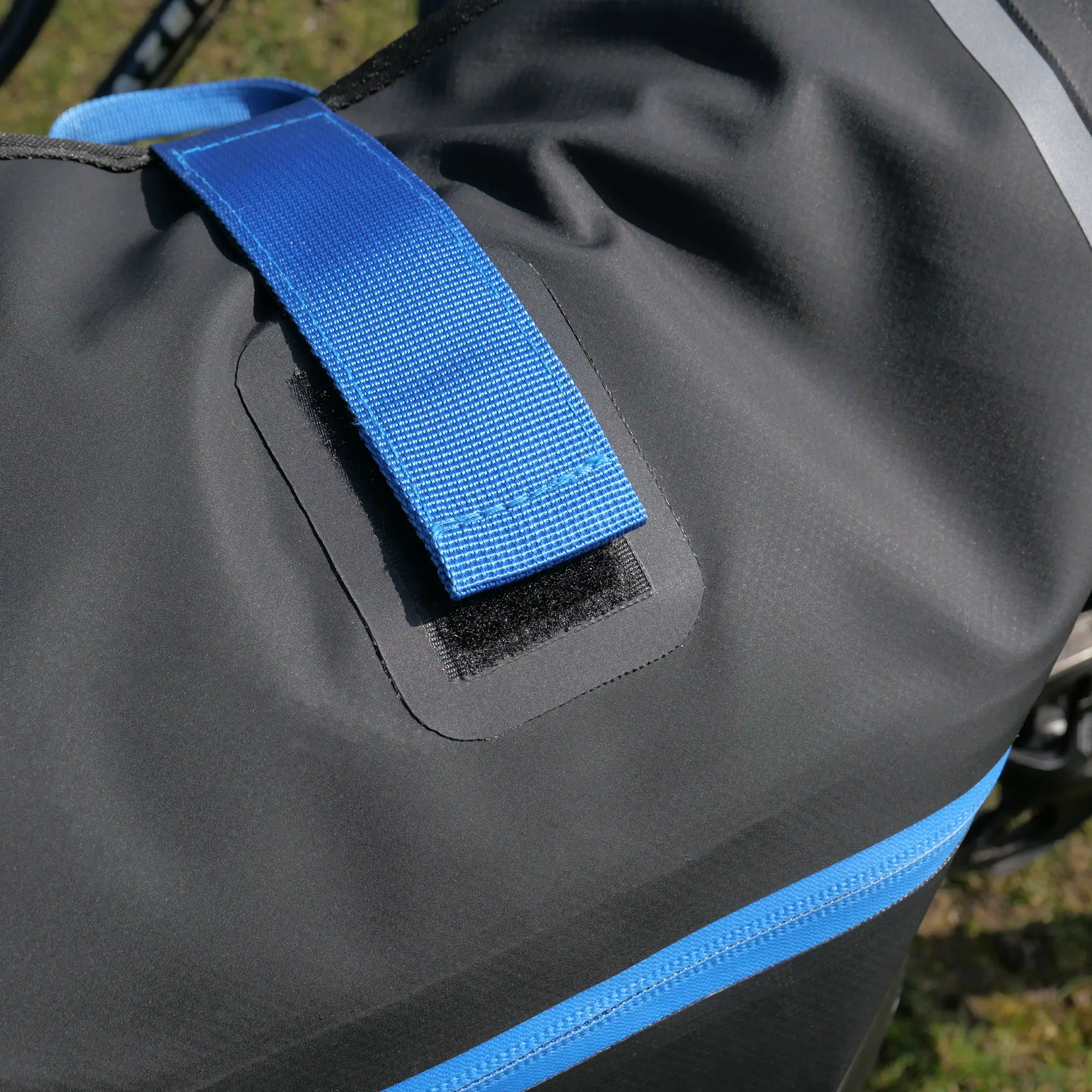 Close-up of the yourGEAR Arco 19 L 3-in-1 waterproof bike pannier, showing the durable black material, blue strap with Velcro, and blue accent zipper, suitable as a pannier, backpack, or laptop bag.