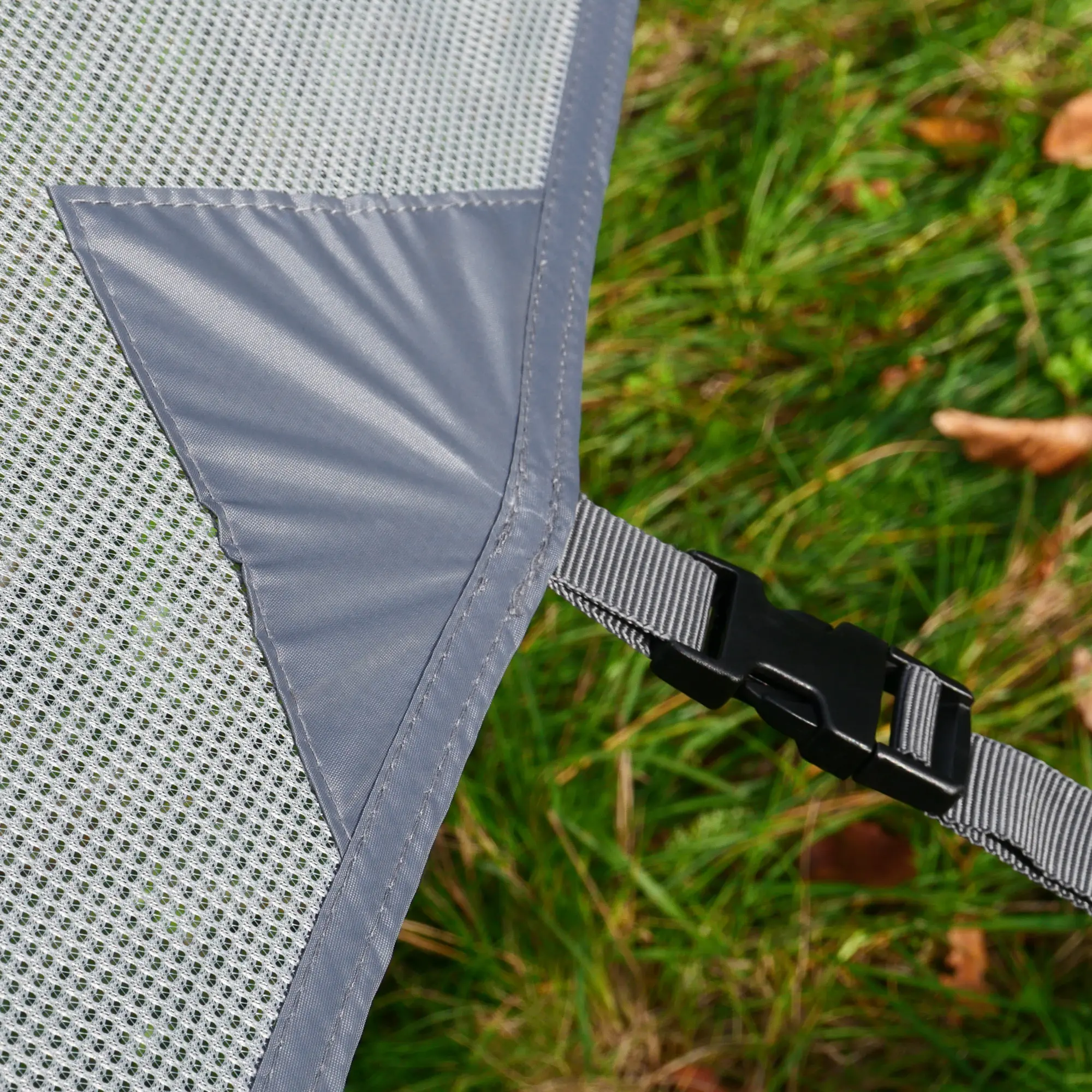 Dettaglio della parete frontale your GEAR Capri Sun Blocker 2,8 x 2 m con tessuto a rete grigia, rinforzo angolare in tessuto impermeabile e cinturino regolabile con fibbia per fissaggio a tendalino da camper o roulotte.