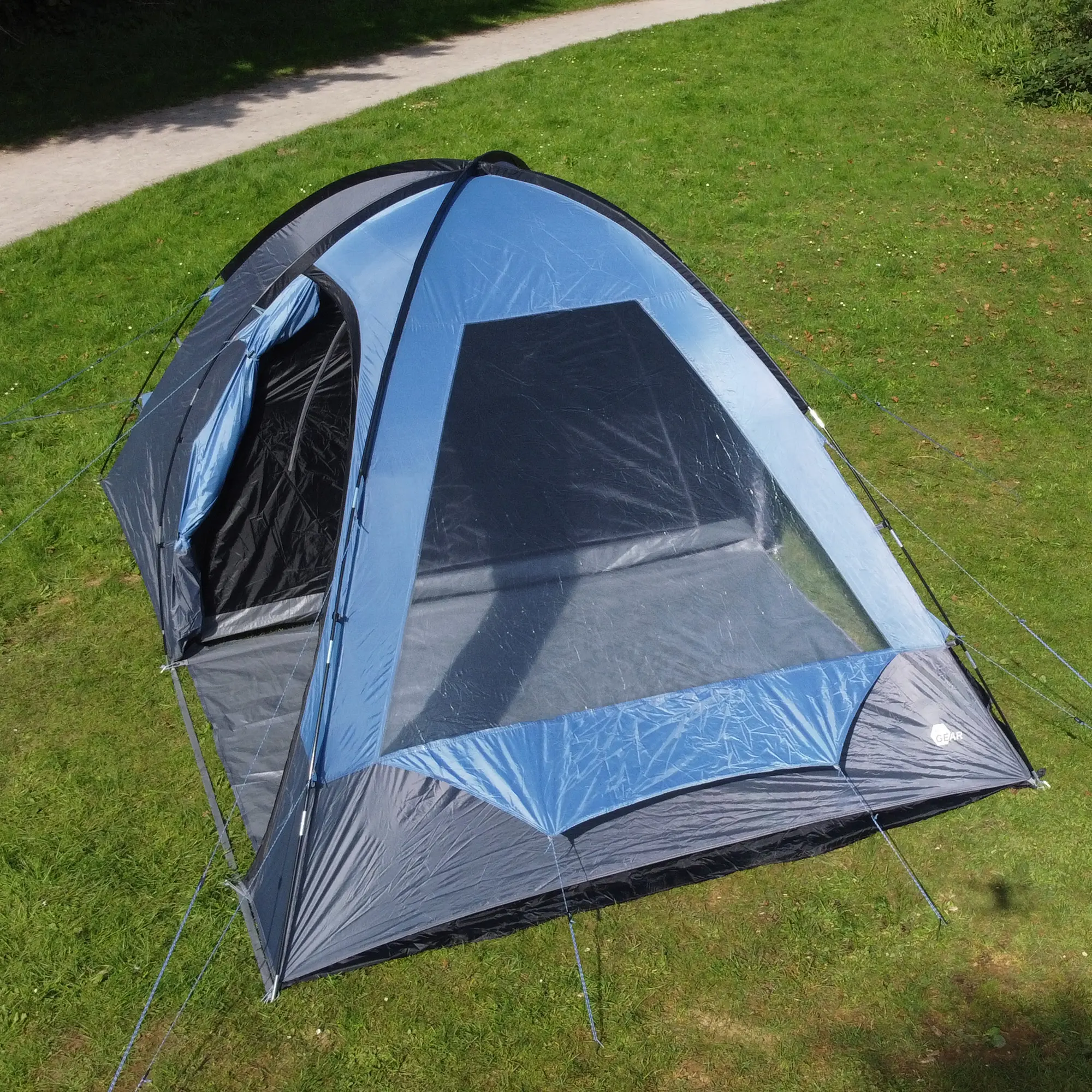 Blau-graues your GEAR Chinook 4 Kuppelzelt für 4 Personen mit großem Wohnraum, Seiteneingang, Fenster und Stehhöhe, auf einer Wiese aufgebaut. Ideal als Familienzelt mit viel Platz und Komfort.