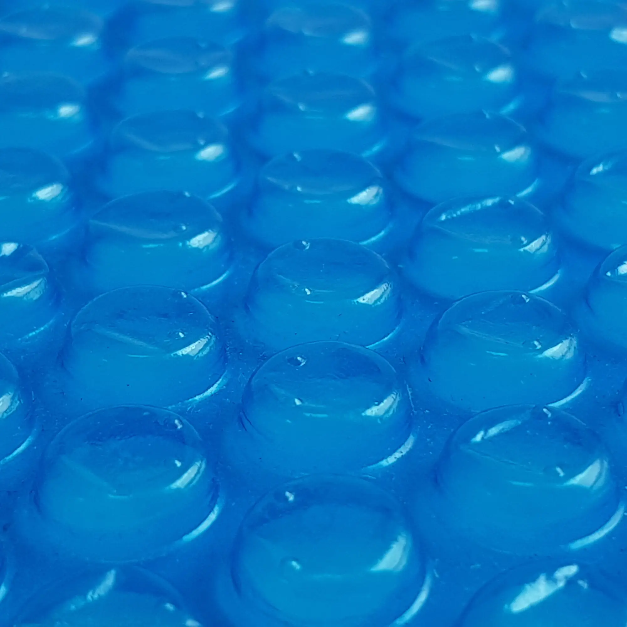 Dettaglio della copertura solare yourGEAR SC-300x300 per piscina, con bolle in rilievo blu da 300 µm, utilizzata per riscaldare l’acqua tramite energia solare e ridurre la dispersione di calore.