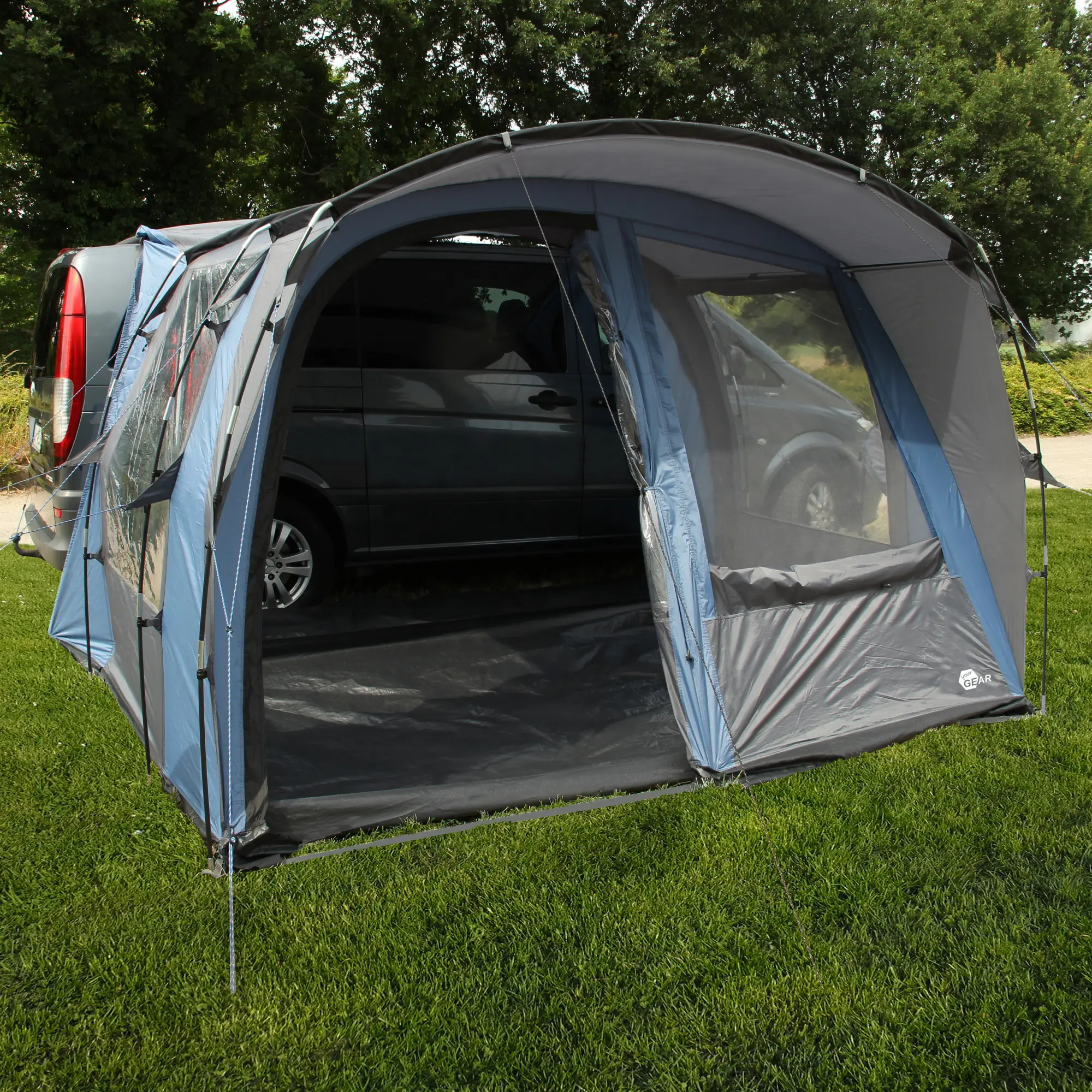 Auvent de bus your GEAR Rimini 300 indépendant, avec grandes fenêtres panoramiques, sol intégré, monté à côté d’un van gris, idéal pour camping, protection UV 50+, couleur bleu-gris.