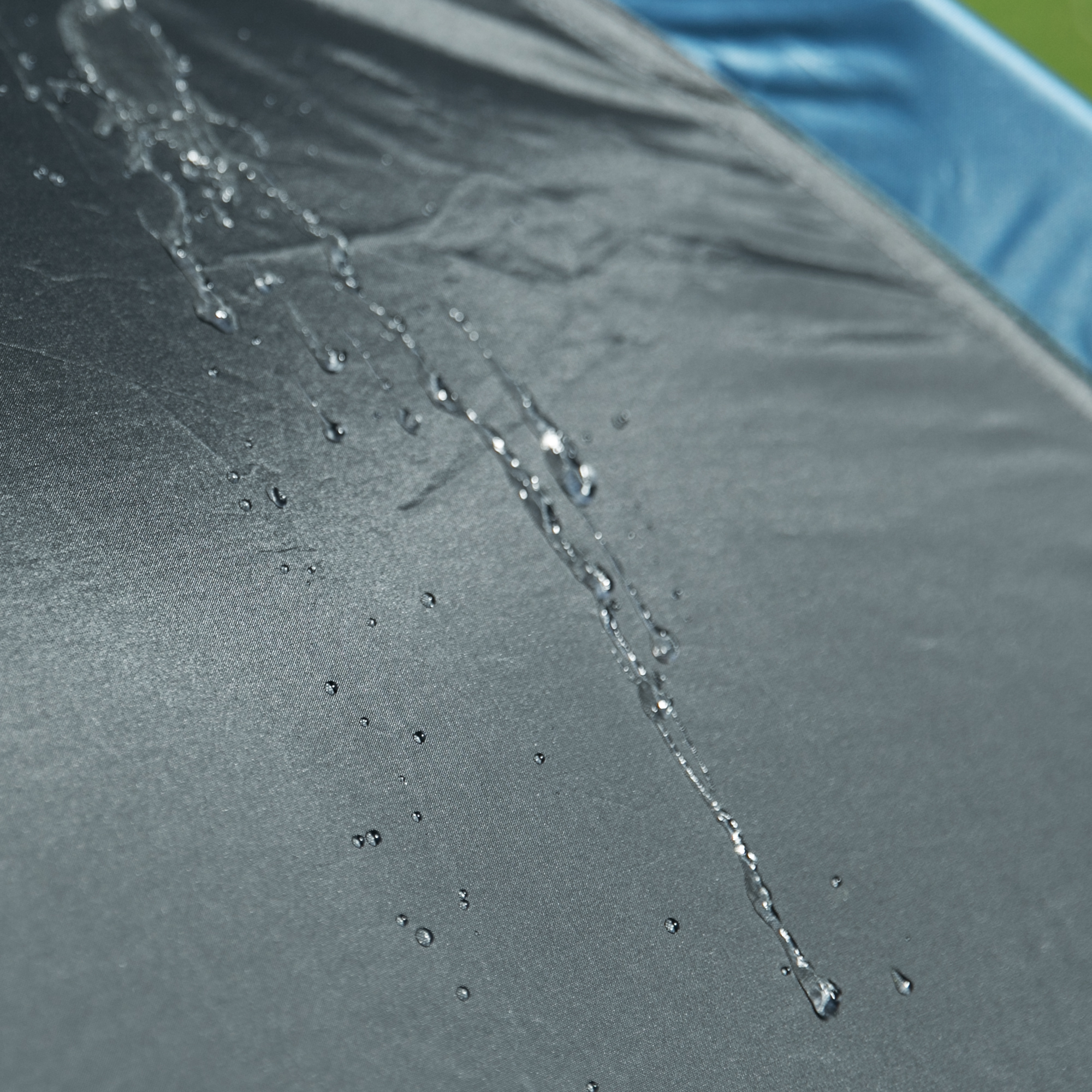 Superficie impermeable del your GEAR Zelt Monza, mostrando gotas de agua resbalando sobre la lona resistente, ideal para 4 personas, protección UV50+ y 3000 mm de columna de agua para camping seguro.