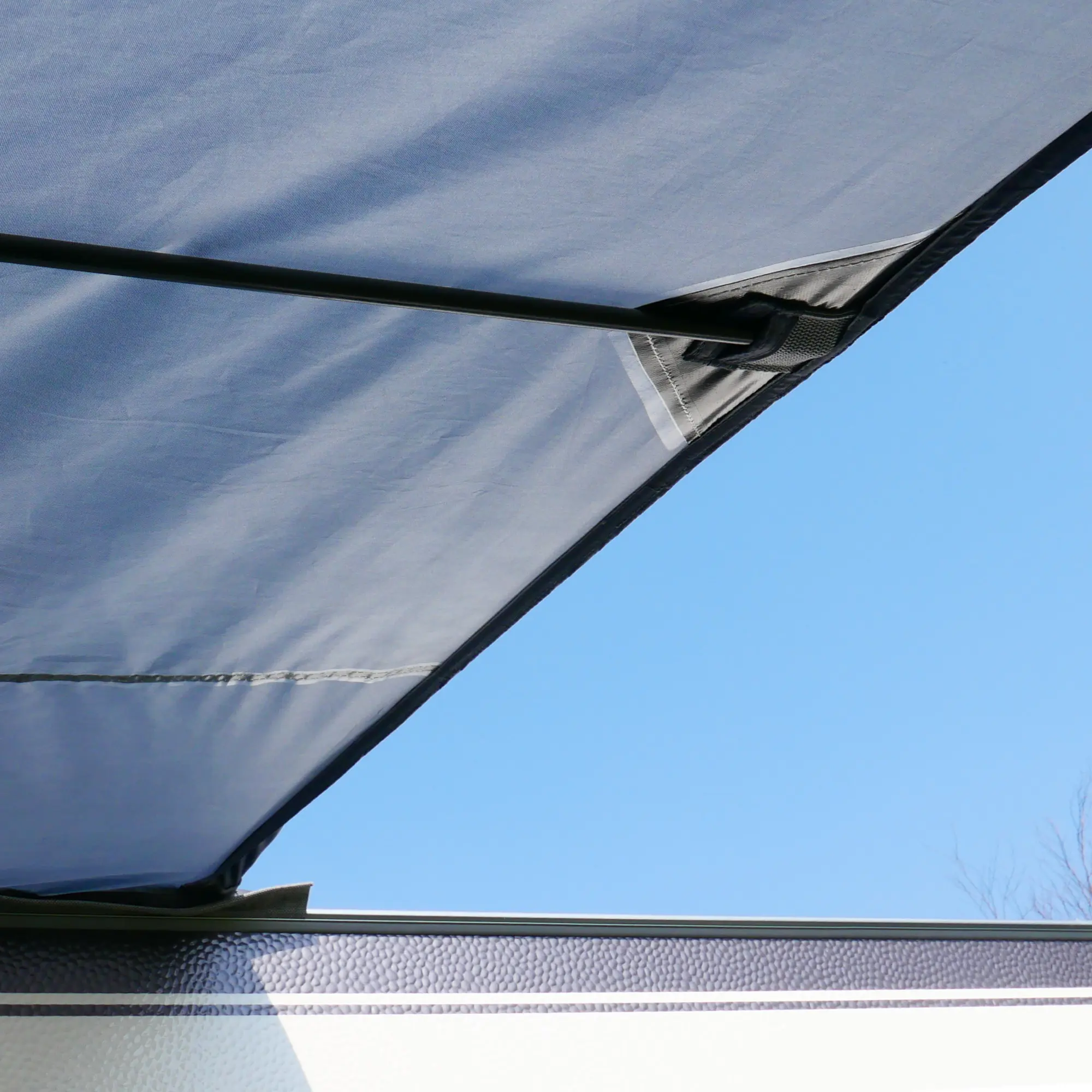 Vordach des your GEAR Riviera 350 Vorzelts am Wohnwagen, stabile Stangenkonstruktion, wetterfestes Material, UV-Schutz 50+, Schutz vor Sonne und Regen, Detailansicht unter blauem Himmel.