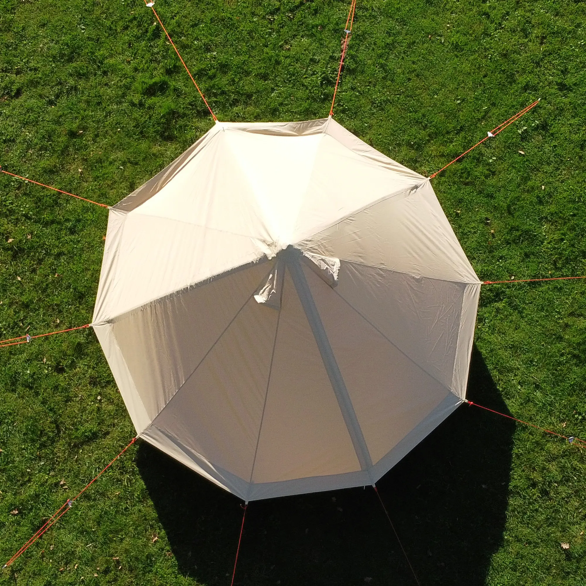 Top view of the your GEAR Gobi 3 tipi tent, beige cotton-polyester fabric, round pyramid shape, no central pole, guy lines for stability, set up on grass, designed for 2-3 people, UV50+ protection.