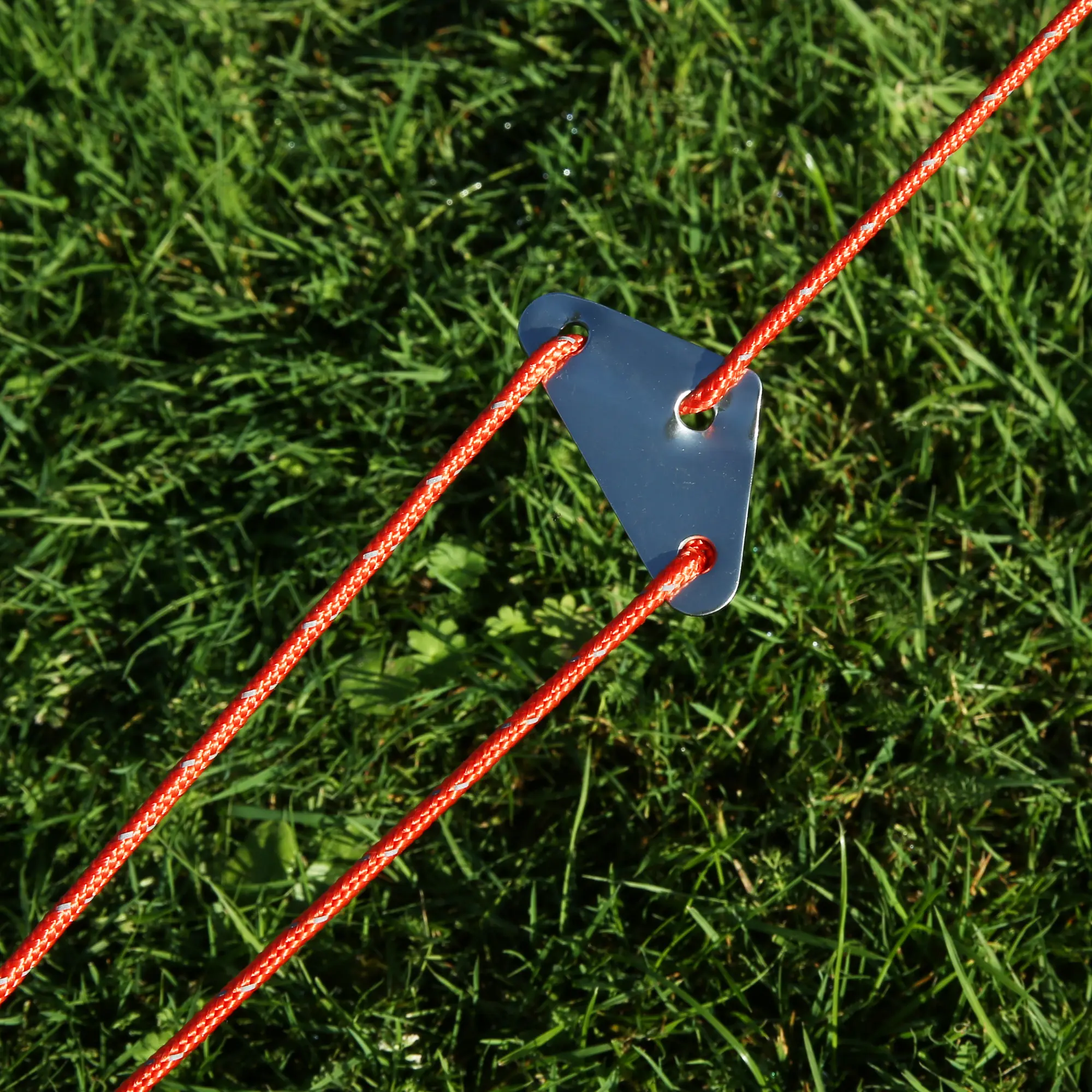 Close-up of the your GEAR Gobi 3 tent guyline system with bright orange ropes and metal tensioner on grass, showing the sturdy, easy-to-use setup for stable pitching of the cotton UV50+ camping tipi tent.