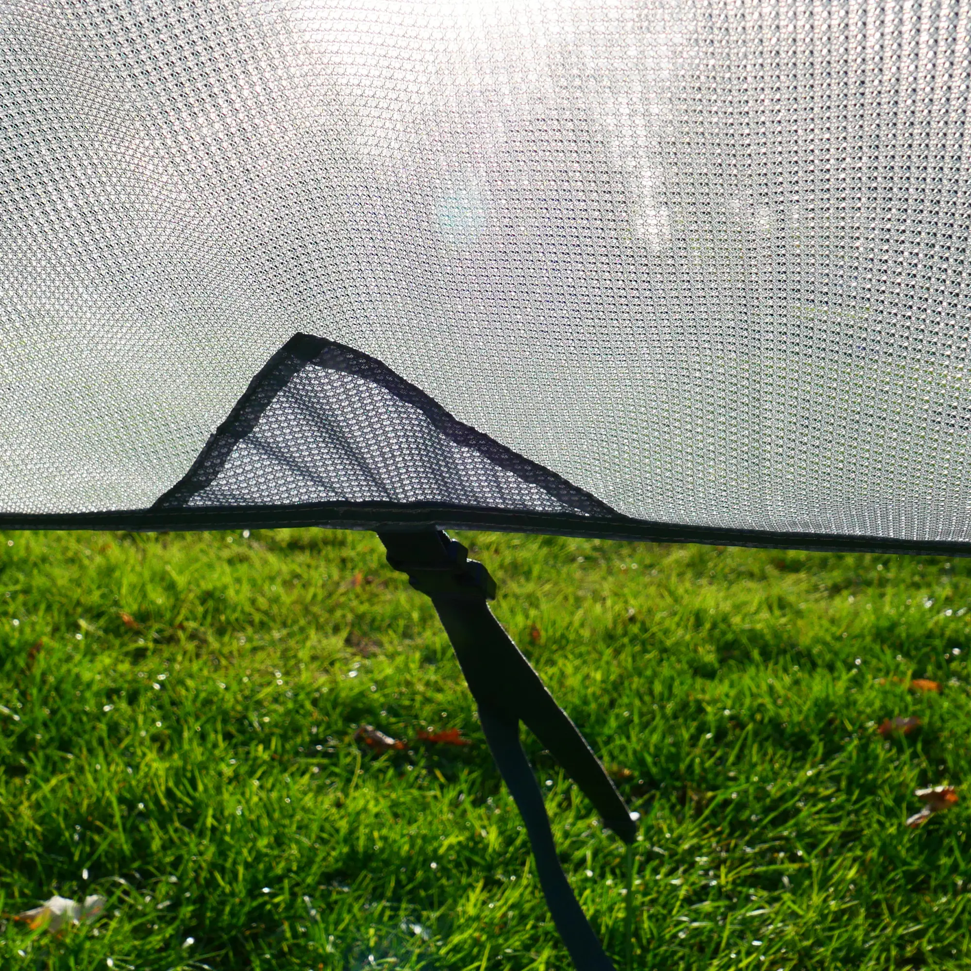 Paroi avant your GEAR Capri Sun Blocker 2,4 x 2 m en tissu spécial filtrant, fixation au sol par sangle, protection solaire pour auvent de camping-car ou caravane, vue sur herbe en arrière-plan.