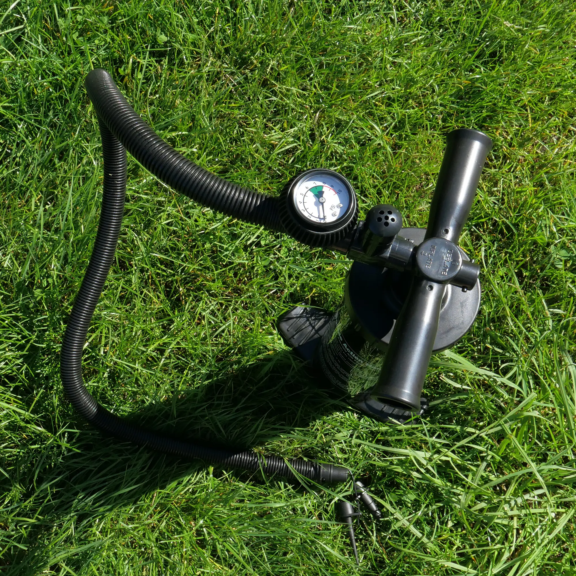 Manual air pump with pressure gauge and flexible hose, suitable for inflating the your GEAR Vicenza 350E AIR inflatable caravan awning, shown on green grass. Essential accessory for easy single inflation system.