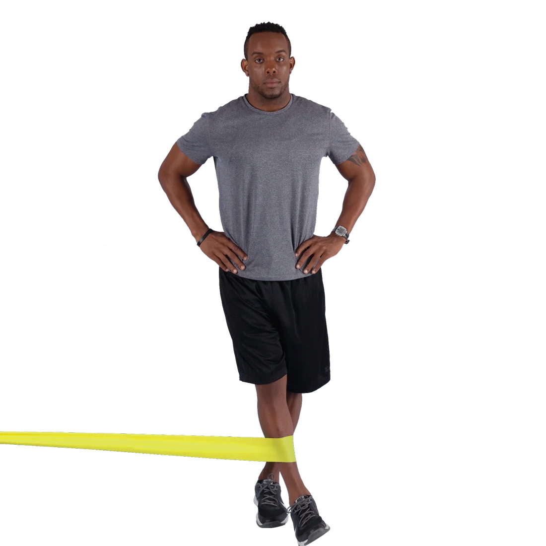 Man using Spirit Fitness Band 9 kg, latex-free resistance band (183x10 cm), yellow color, for lower body exercise. Fitness band is stretched around his legs, demonstrating strength training use.
