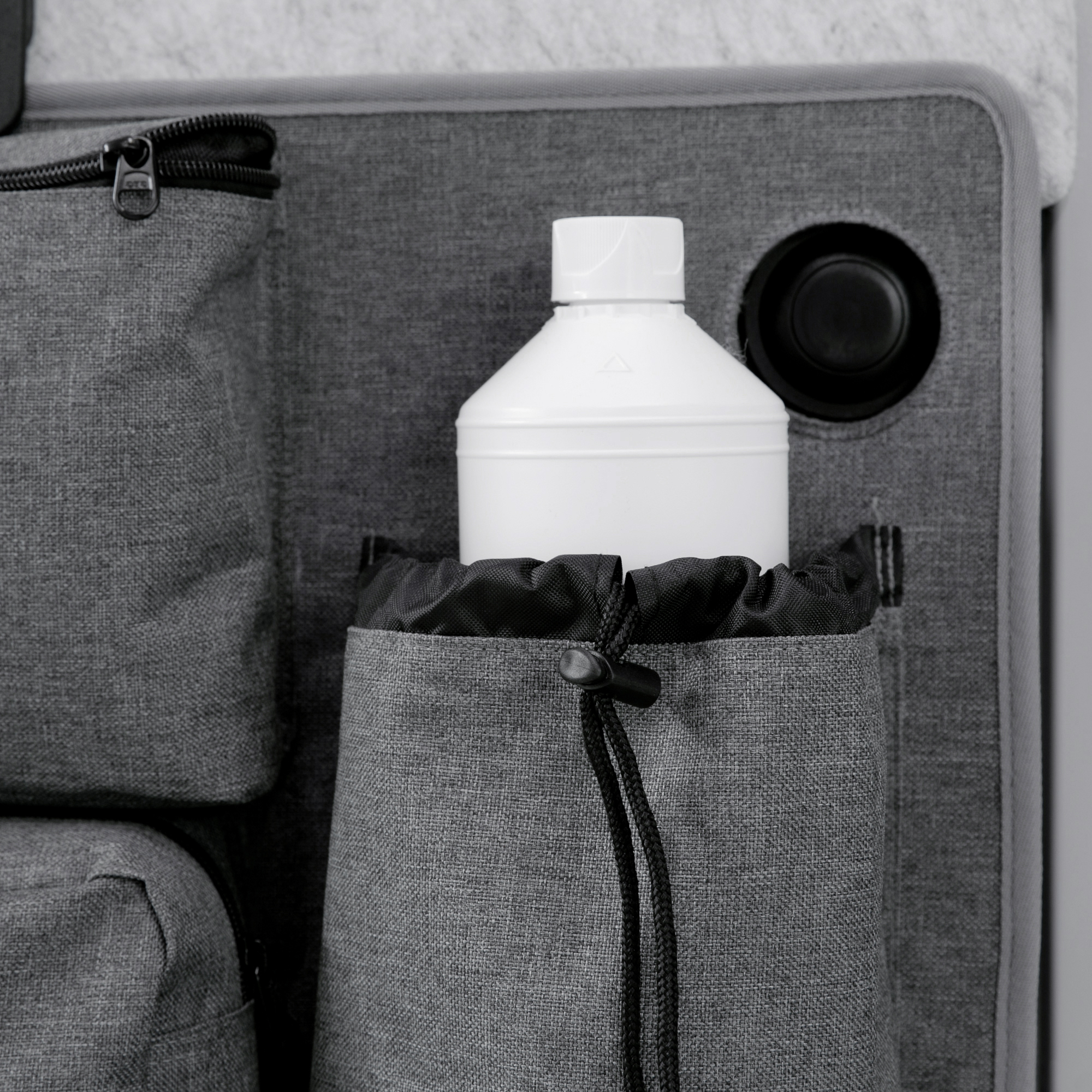 Organisateur your GEAR Ortles L pour porte arrière gauche de camping-car, avec poches robustes grises de différentes tailles, dont une contenant une bouteille blanche et fermetures à cordon et à glissière visibles.
