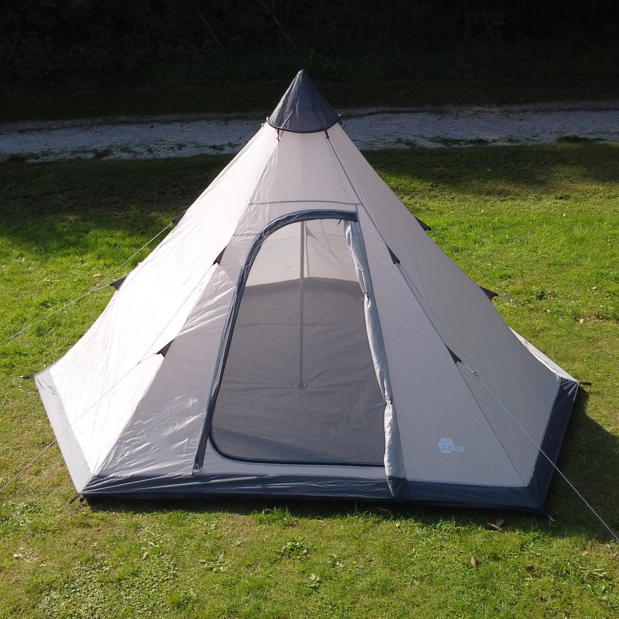 your GEAR Lido 370 tipi tent for 4 people, shown pitched on grass. Features include a pyramid shape, high entrance with mesh insect protection, sewn-in bathtub floor, and waterproof light-grey fabric.