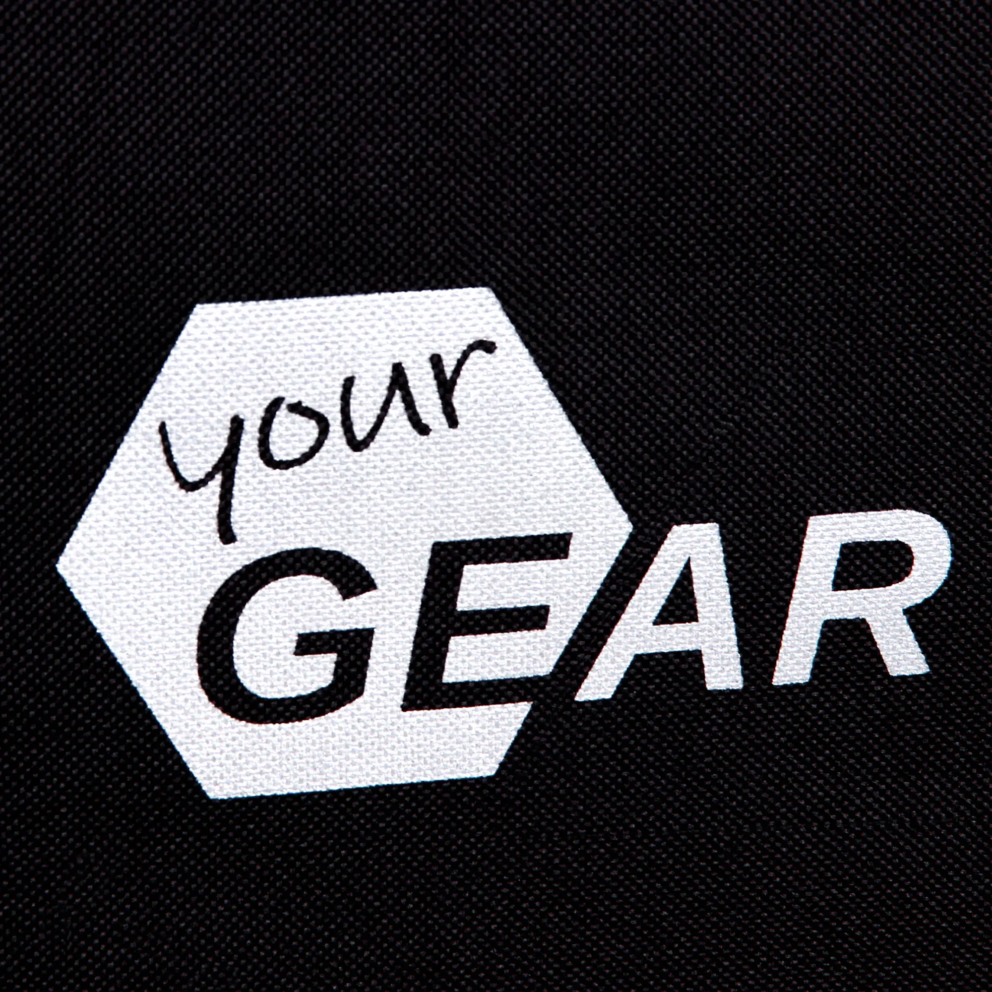 Logo yourGEAR auf schwarzem Stoff, sechseckiges weißes Emblem mit Schriftzug „your GEAR“, deutlicher Markenaufdruck eines XXL faltbaren Bollerwagens für Camping und Outdoor.