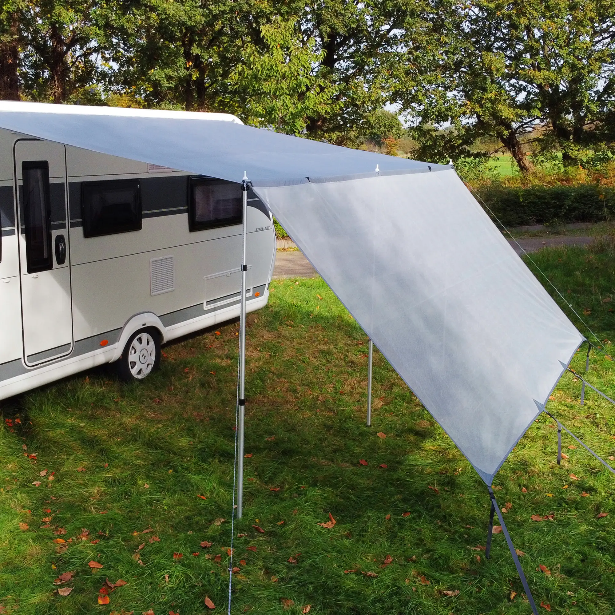 your GEAR Procida sun blocker front wall 300x200 cm attached to a caravan canopy, shown as a light grey fabric panel supported by three poles, providing sun and privacy protection for campers.