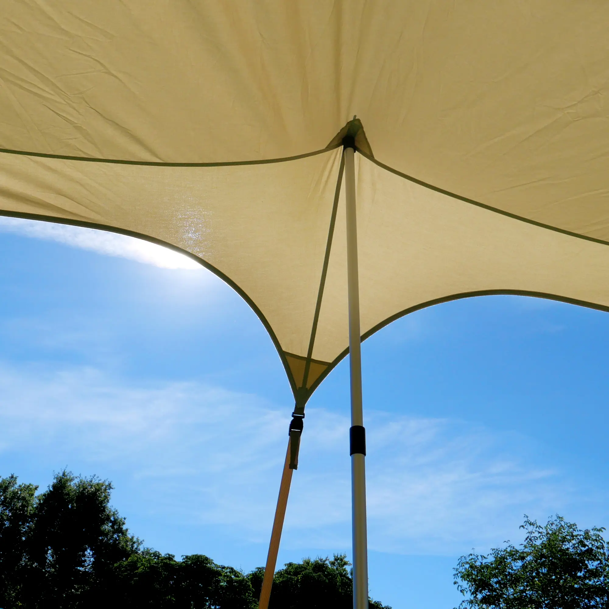 Beiges your GEAR Scilla TC Caravan Sonnensegel 400x250 cm mit stabilen Stangen, aufgespannt unter blauem Himmel, bietet UV-Schutz und Schatten für Wohnwagen oder Wohnmobil, atmungsaktives Material erkennbar.