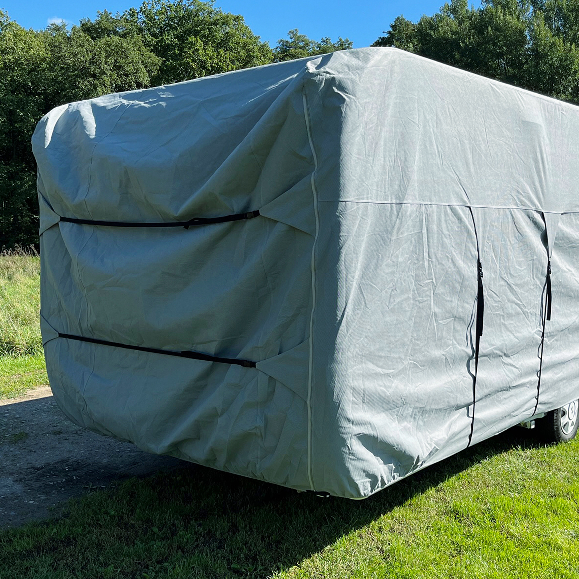 Grey your GEAR Bonito 430-470 caravan cover made of four-layer material, fully covering a caravan, with securing straps visible, designed for caravans 230-250 cm wide and 430-470 cm long, outdoors on grass.