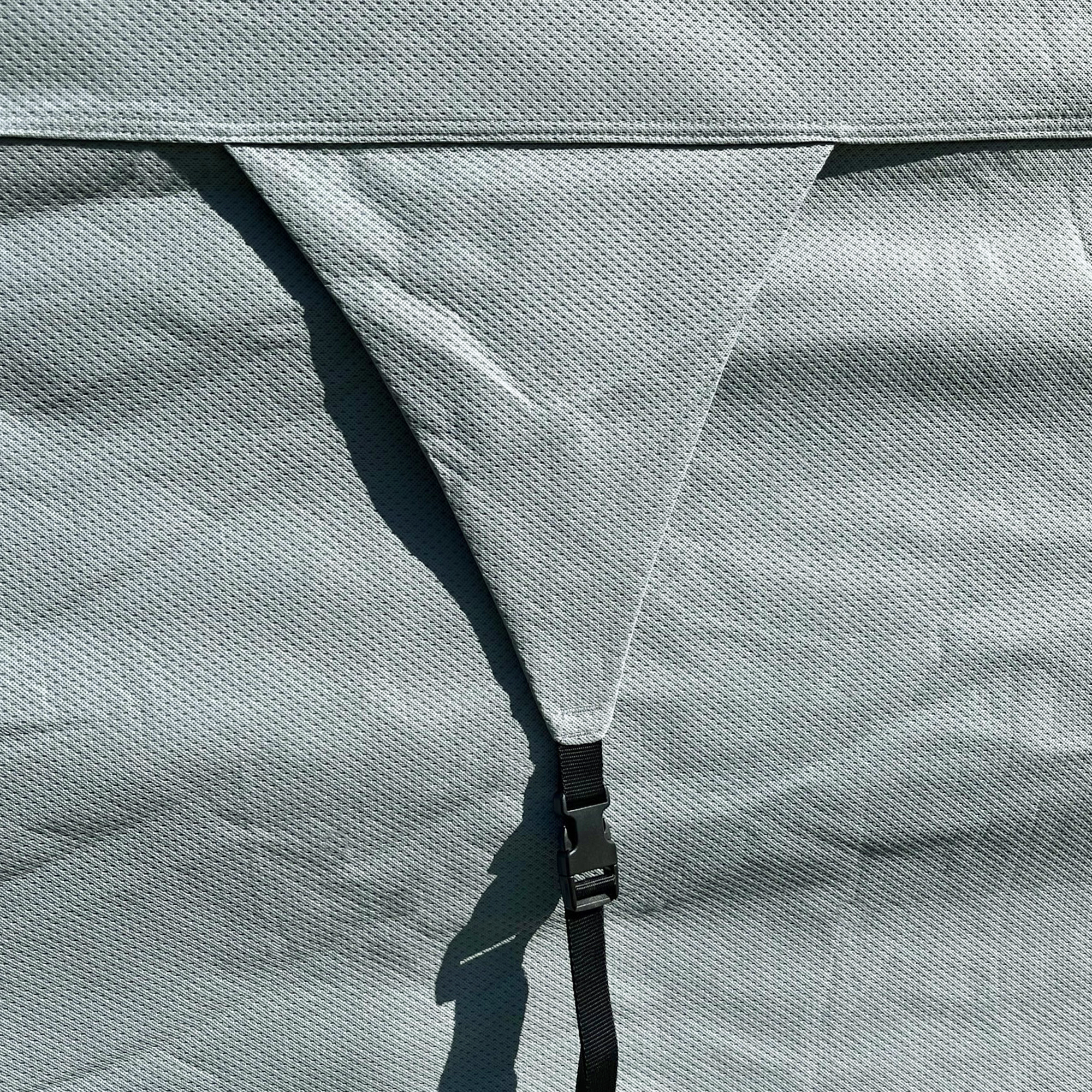 Detailansicht der grauen your GEAR Naro L/XL Wohnwagenabdeckung aus 4-lagigem Material mit atmungsaktiver Struktur, sichtbarer Naht und schwarzem Befestigungsgurt mit Klickverschluss.